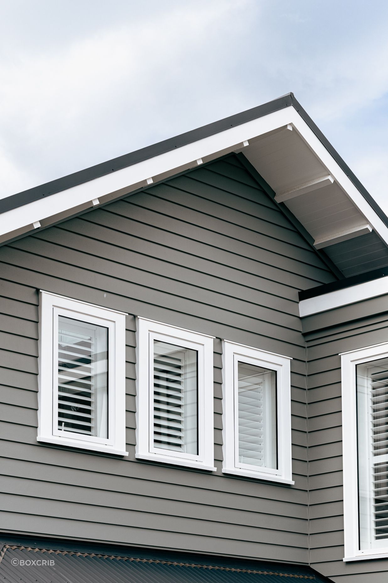 The weatherboard cladding contrasts sharply against the white joinery and soffit details.