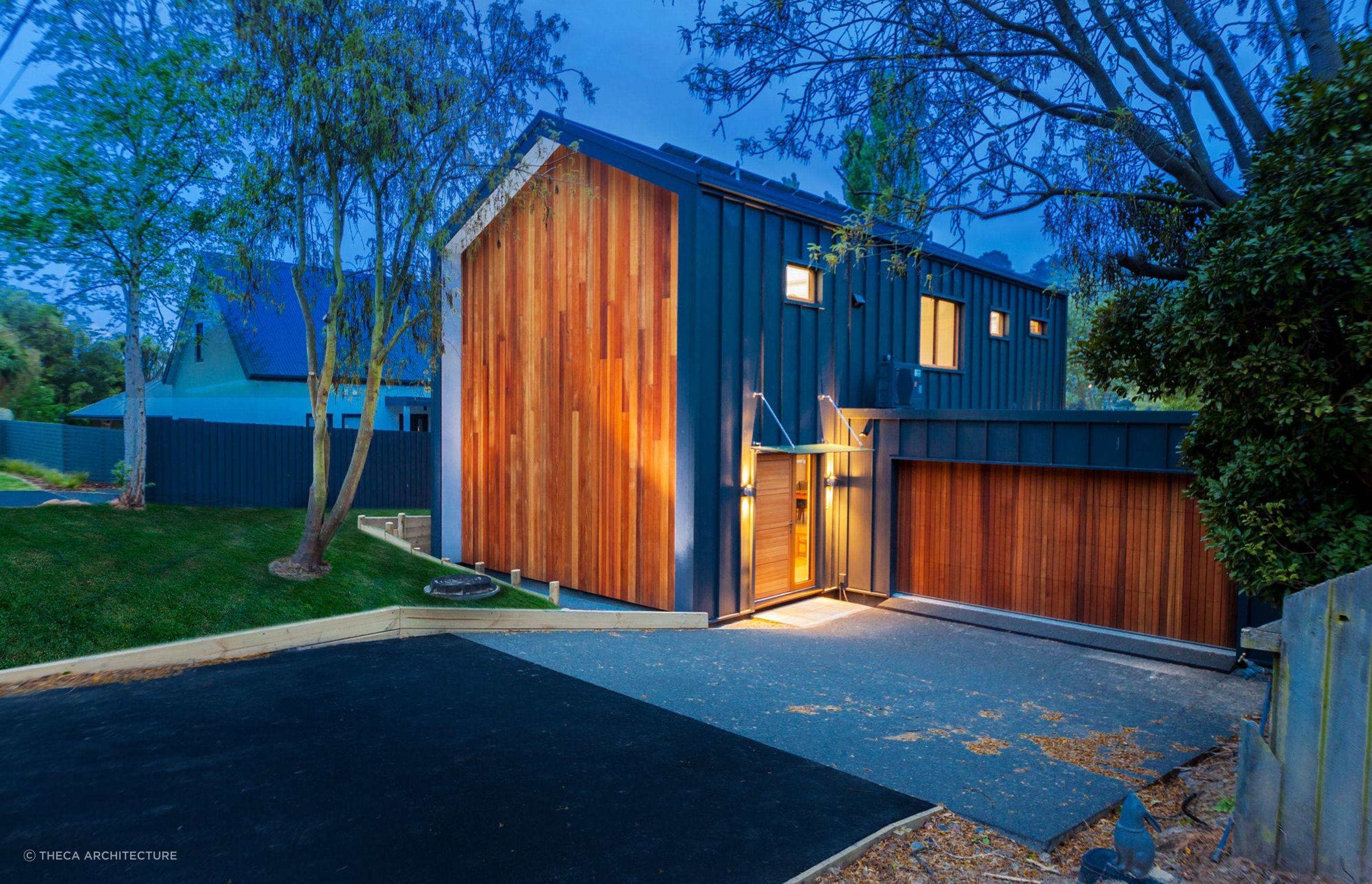 The entryway of the Pitkin-Douglas Passive House at night where solar panel-cladding can be seen on the north-facing roof.