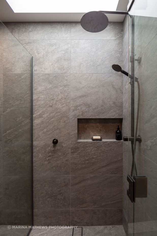 The fully tiled guest shower drinks in the light from an overhead aperture.