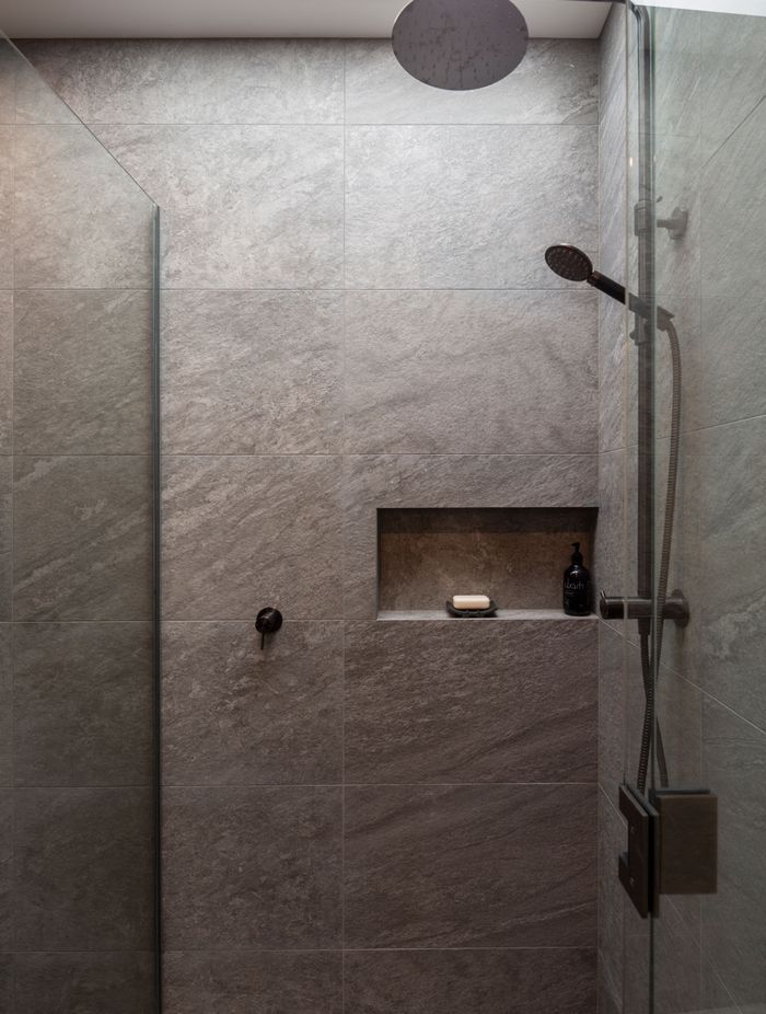 The fully tiled guest shower drinks in the light from an overhead aperture.