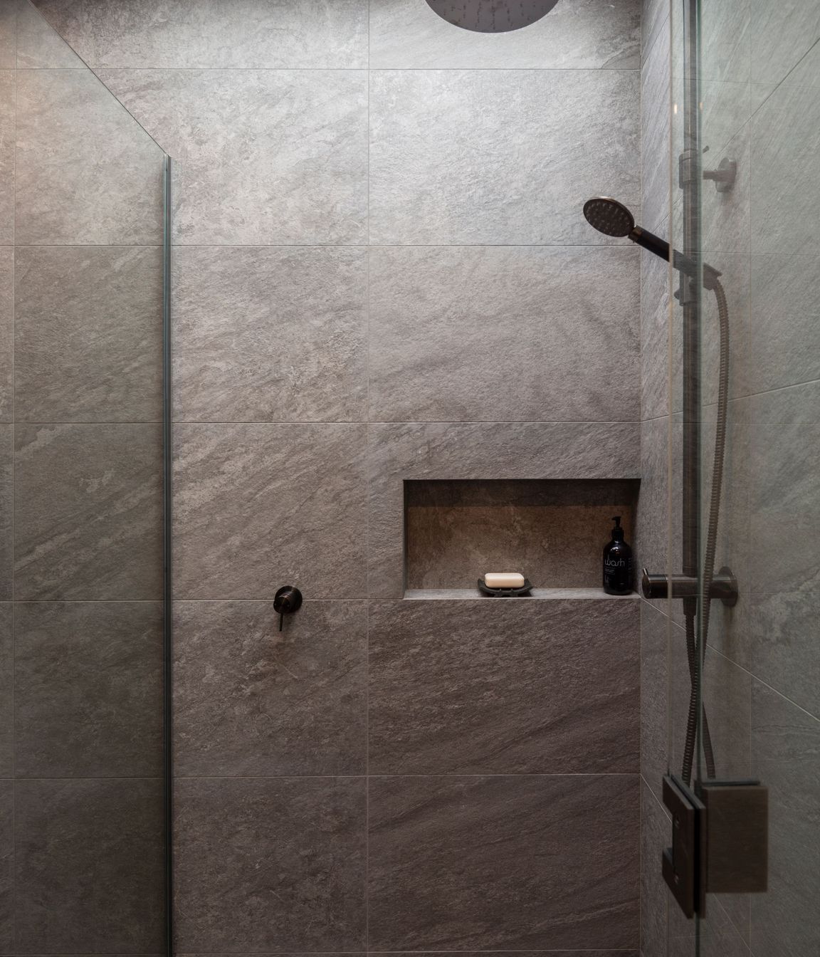 The fully tiled guest shower drinks in the light from an overhead aperture.