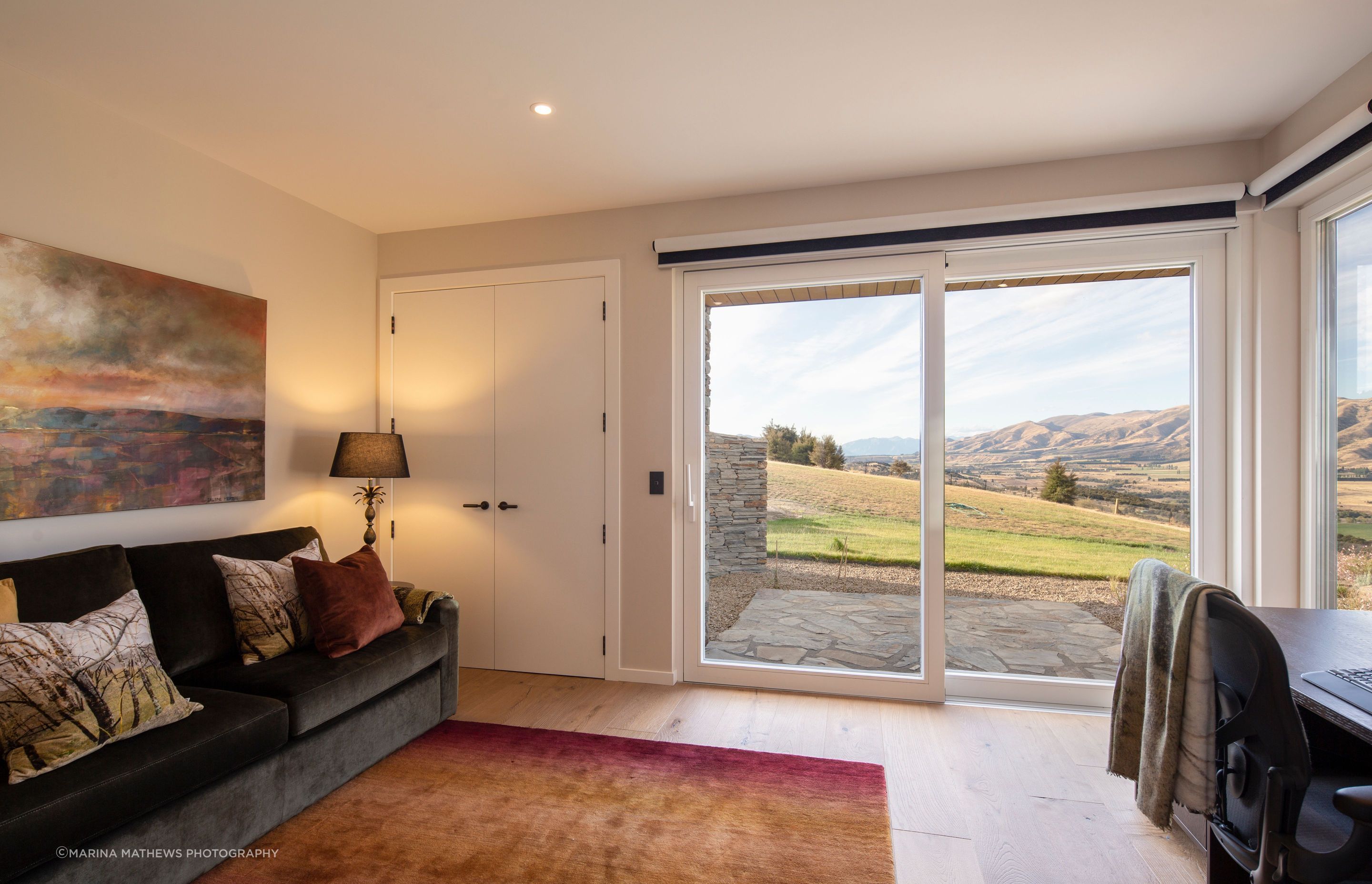 The study/guest room featuring oak desk and custom-designed couch offers stunning views of the landscape.