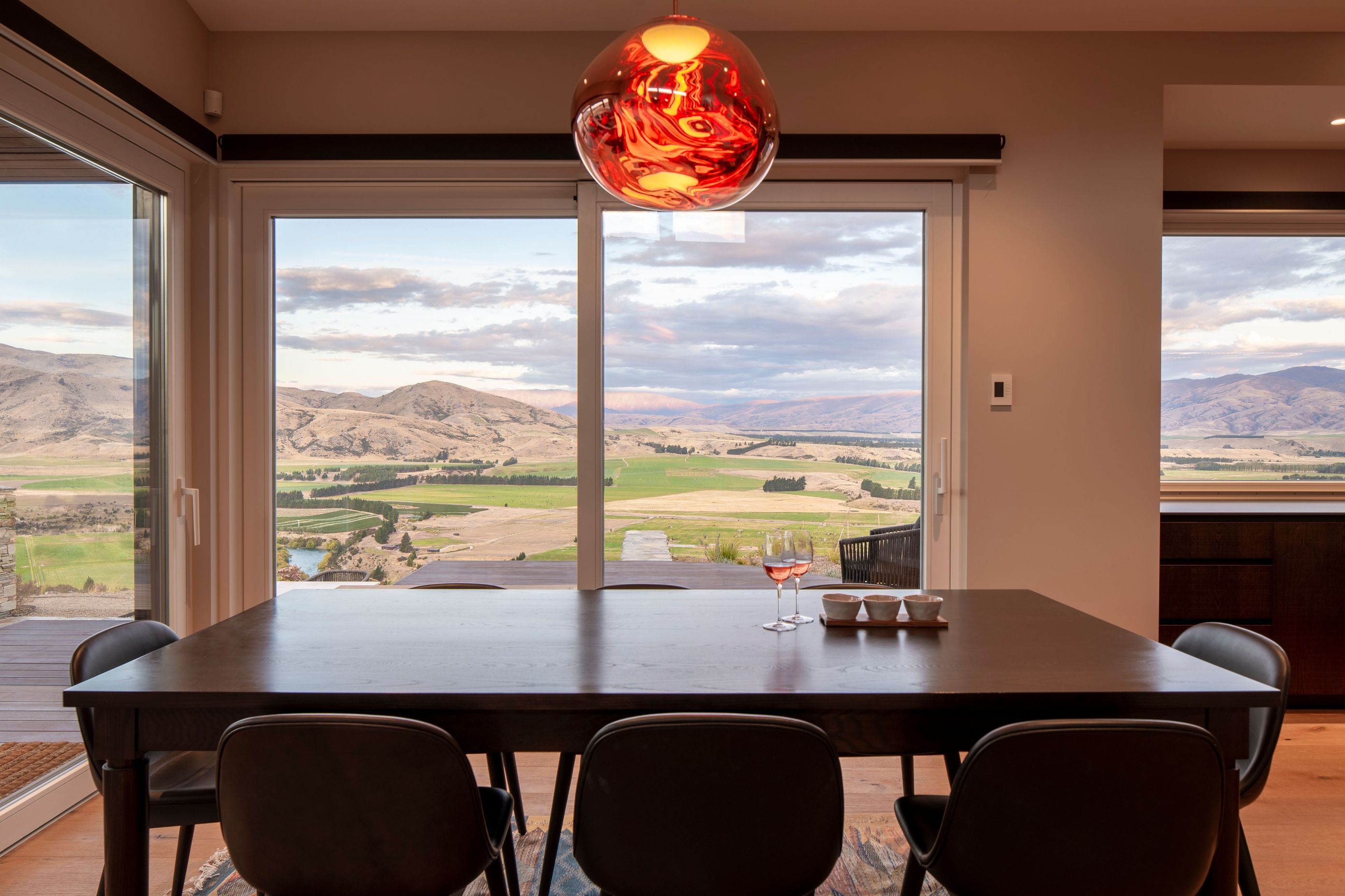 The custom designed dining table in rich dark timber drinks in views of the landscape.