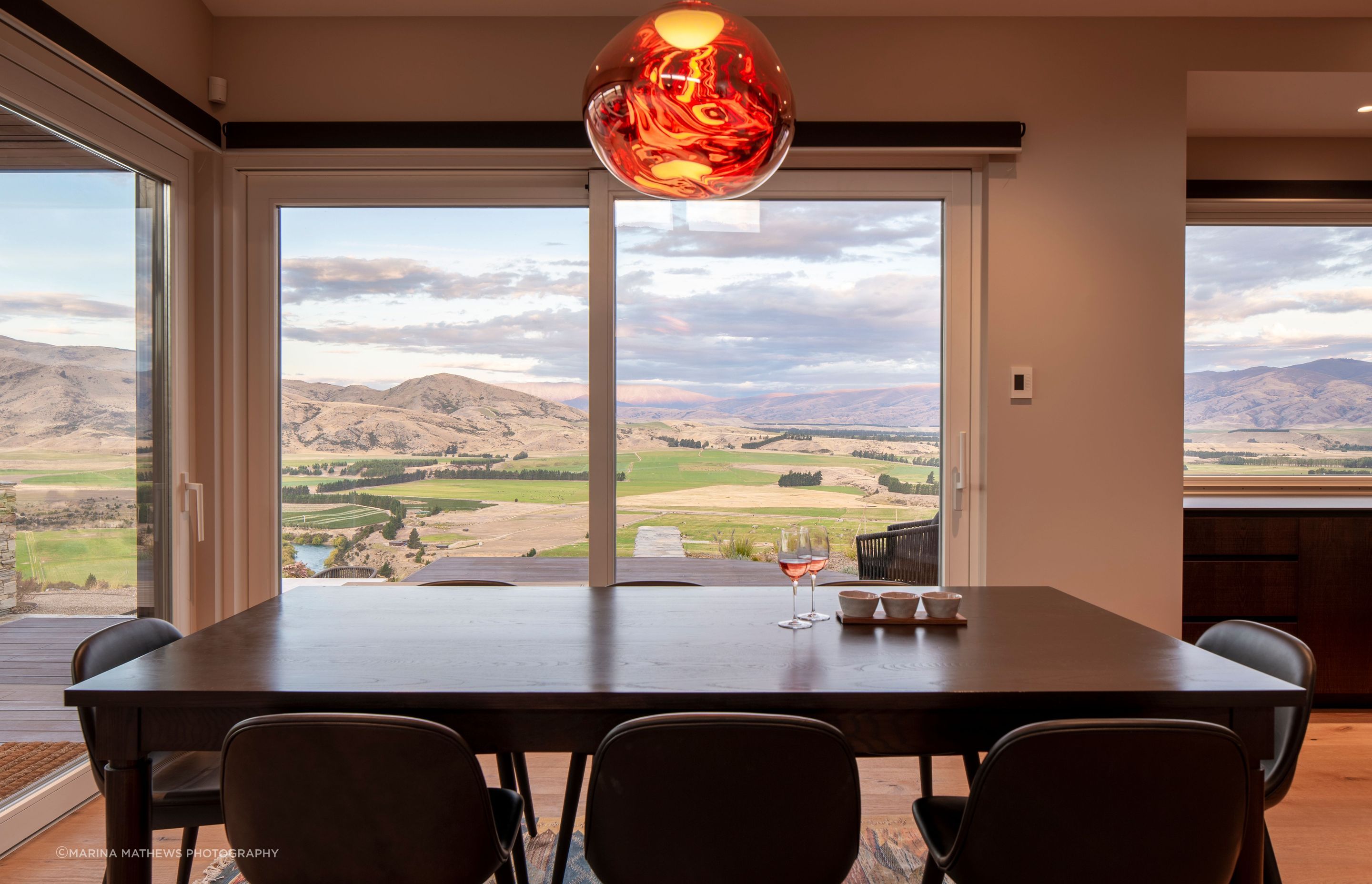 The custom designed dining table in rich dark timber drinks in views of the landscape.
