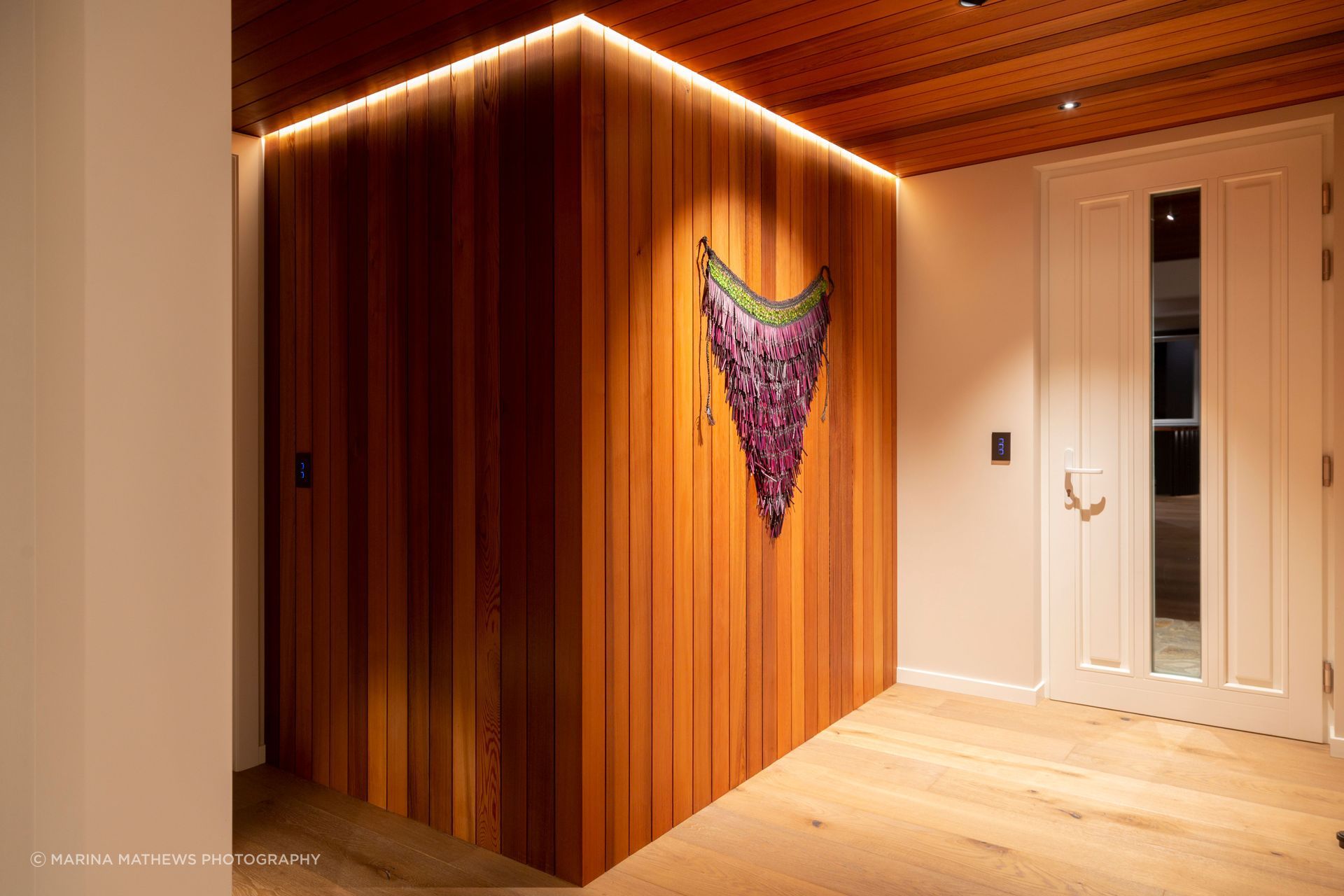 The entryway features cedar cladding and ceiling, contrasted with pale oak floors.