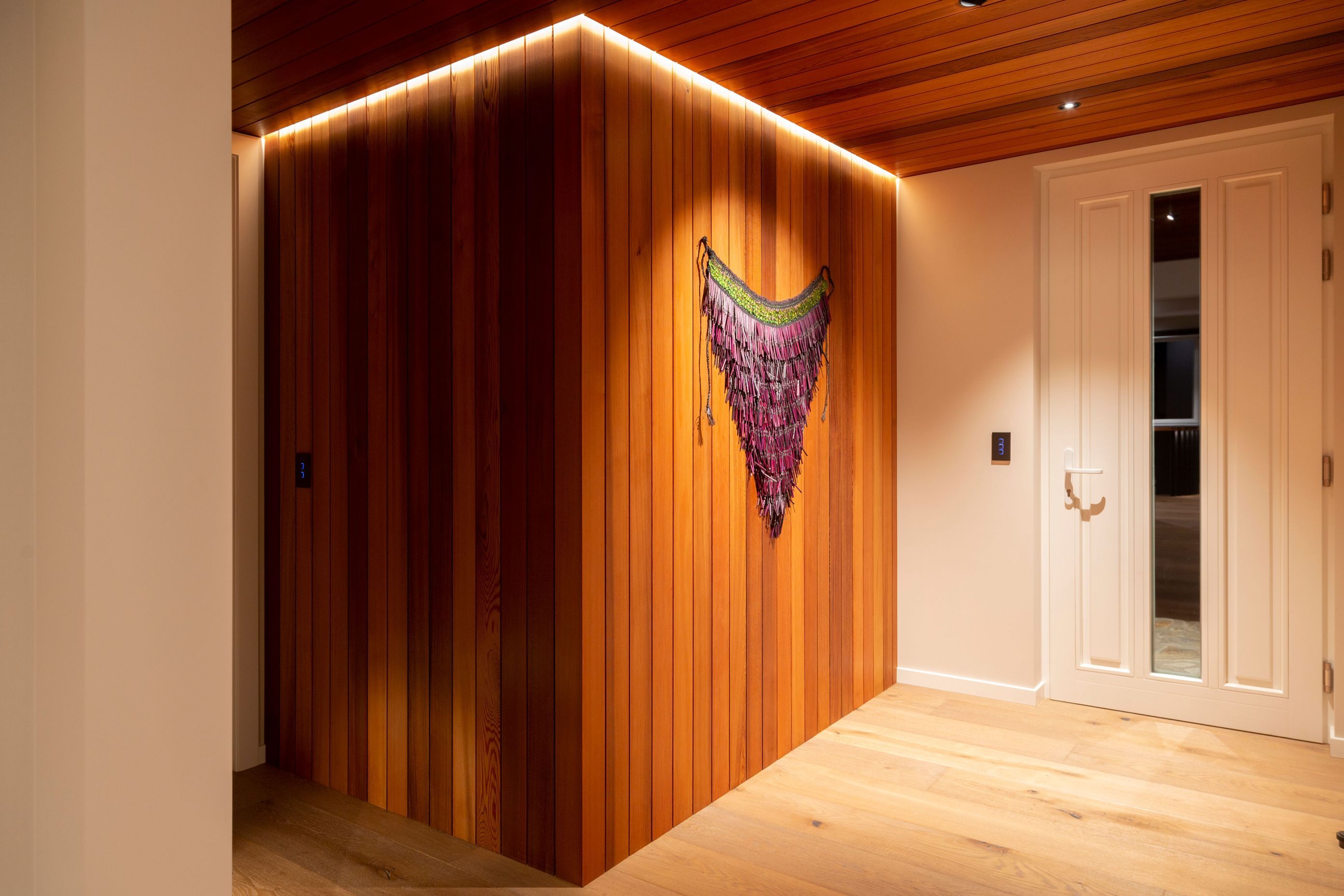 The entryway features cedar cladding and ceiling, contrasted with pale oak floors.