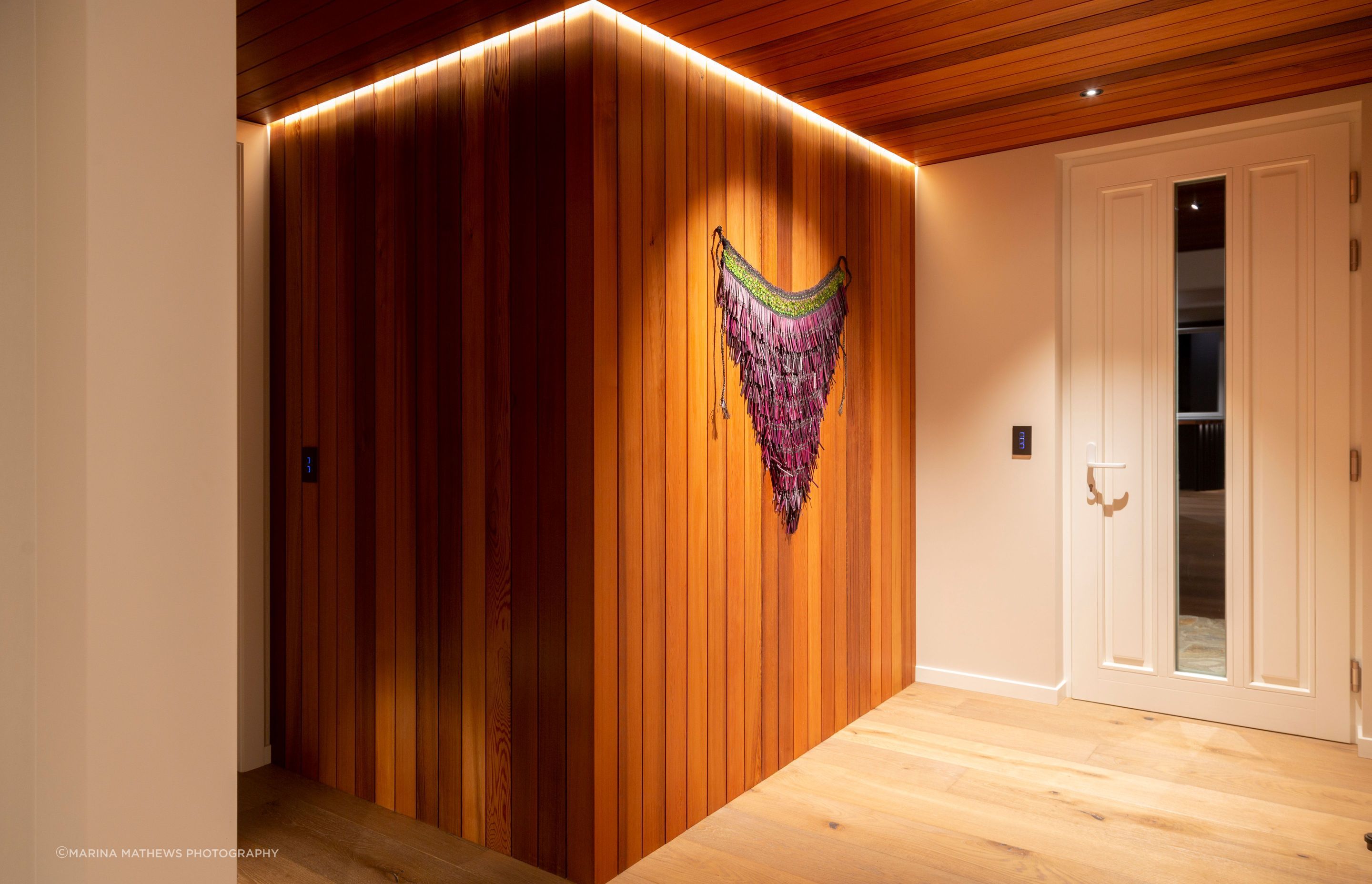 The entryway features cedar cladding and ceiling, contrasted with pale oak floors.