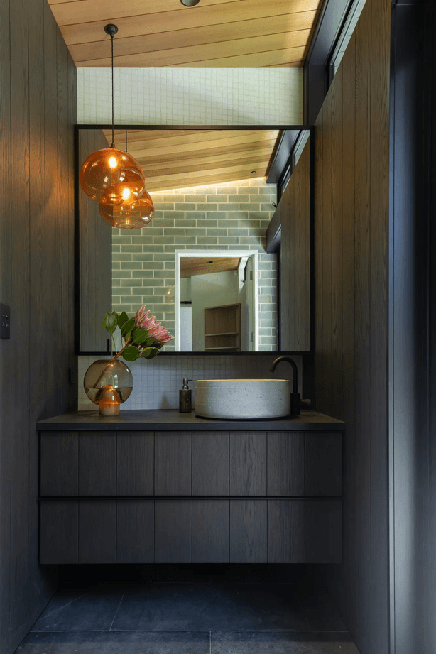The master room’s ensuite, designed with custom cabinetry, handmade tiles, and a feature pendant light that hangs in counterbalance to the clerestory windows.