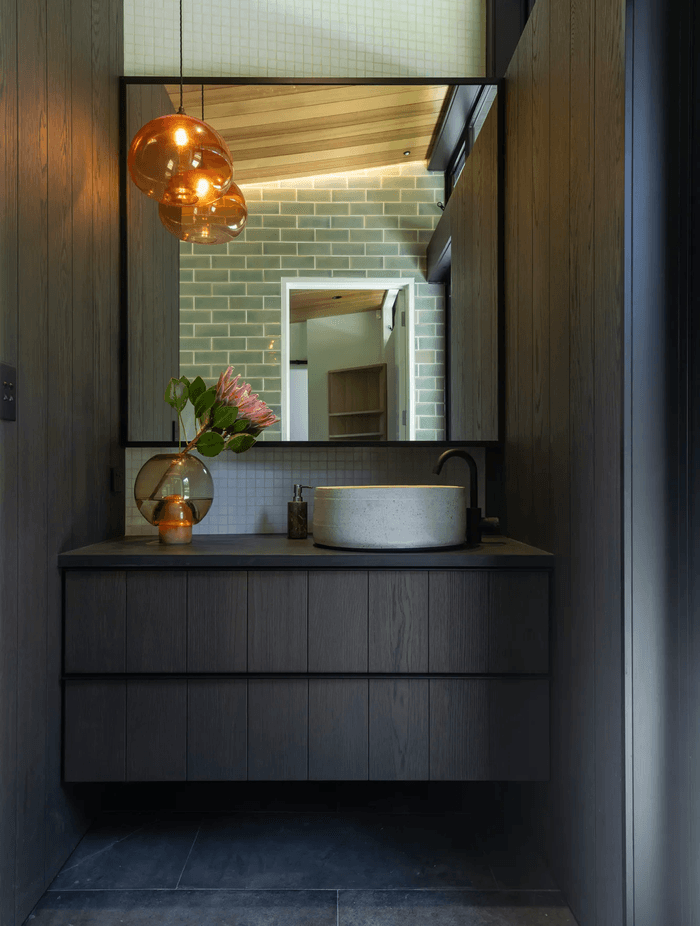 The master room’s ensuite, designed with custom cabinetry, handmade tiles, and a feature pendant light that hangs in counterbalance to the clerestory windows.