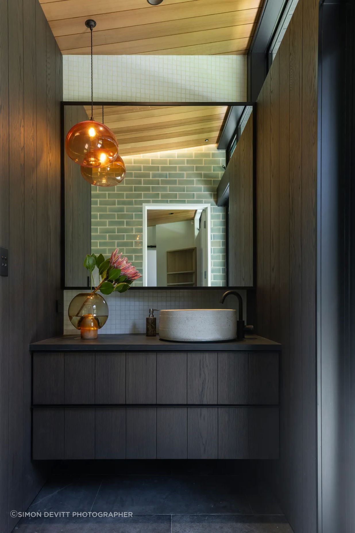 The master room’s ensuite, designed with custom cabinetry, handmade tiles, and a feature pendant light that hangs in counterbalance to the clerestory windows.