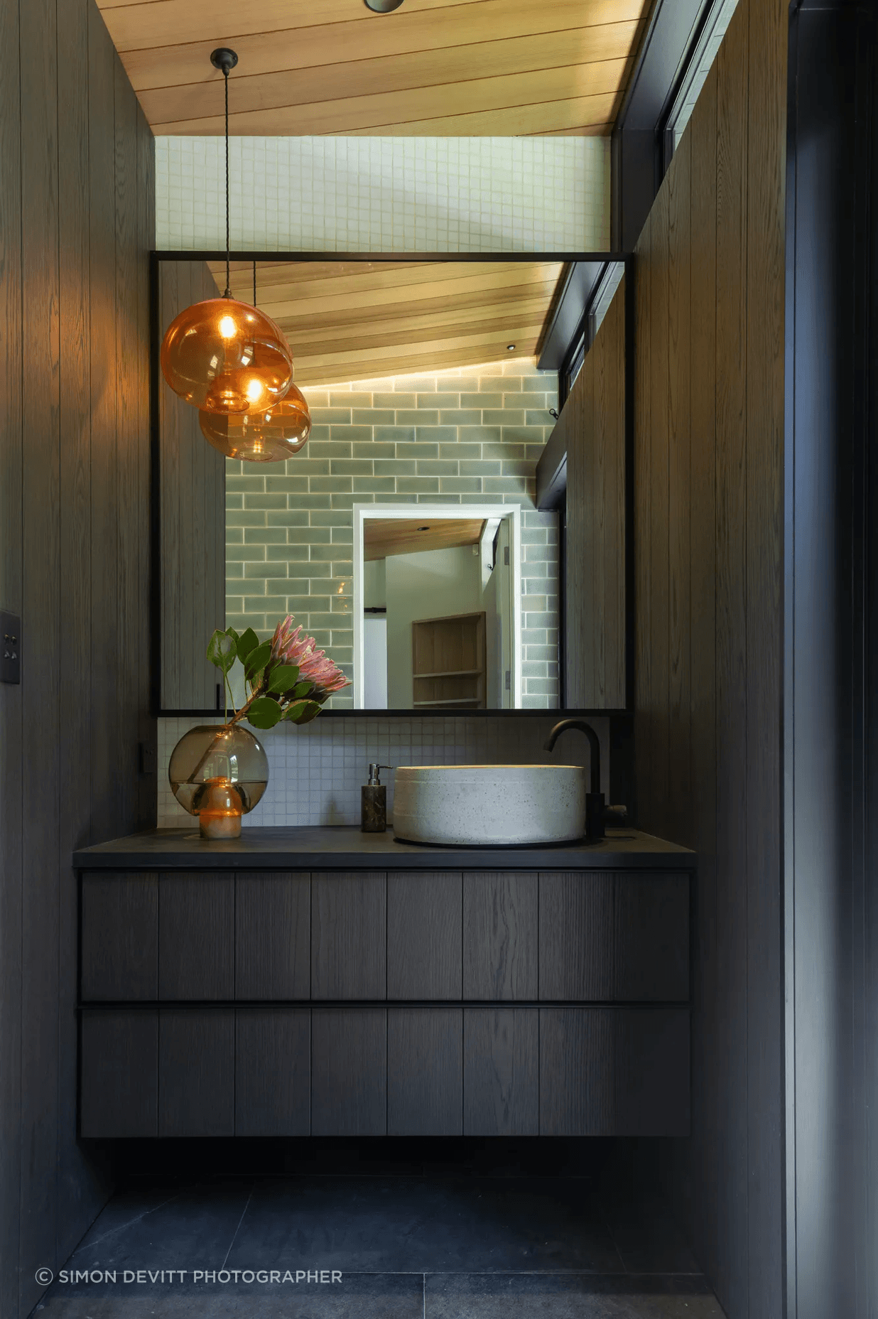 The master room’s ensuite, designed with custom cabinetry, handmade tiles, and a feature pendant light that hangs in counterbalance to the clerestory windows.
