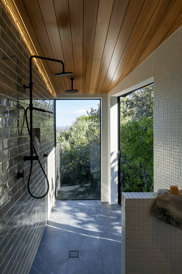 The master room’s ensuite extends into a spacious walk-in shower, with a large sliding door to the right that appears as a window.