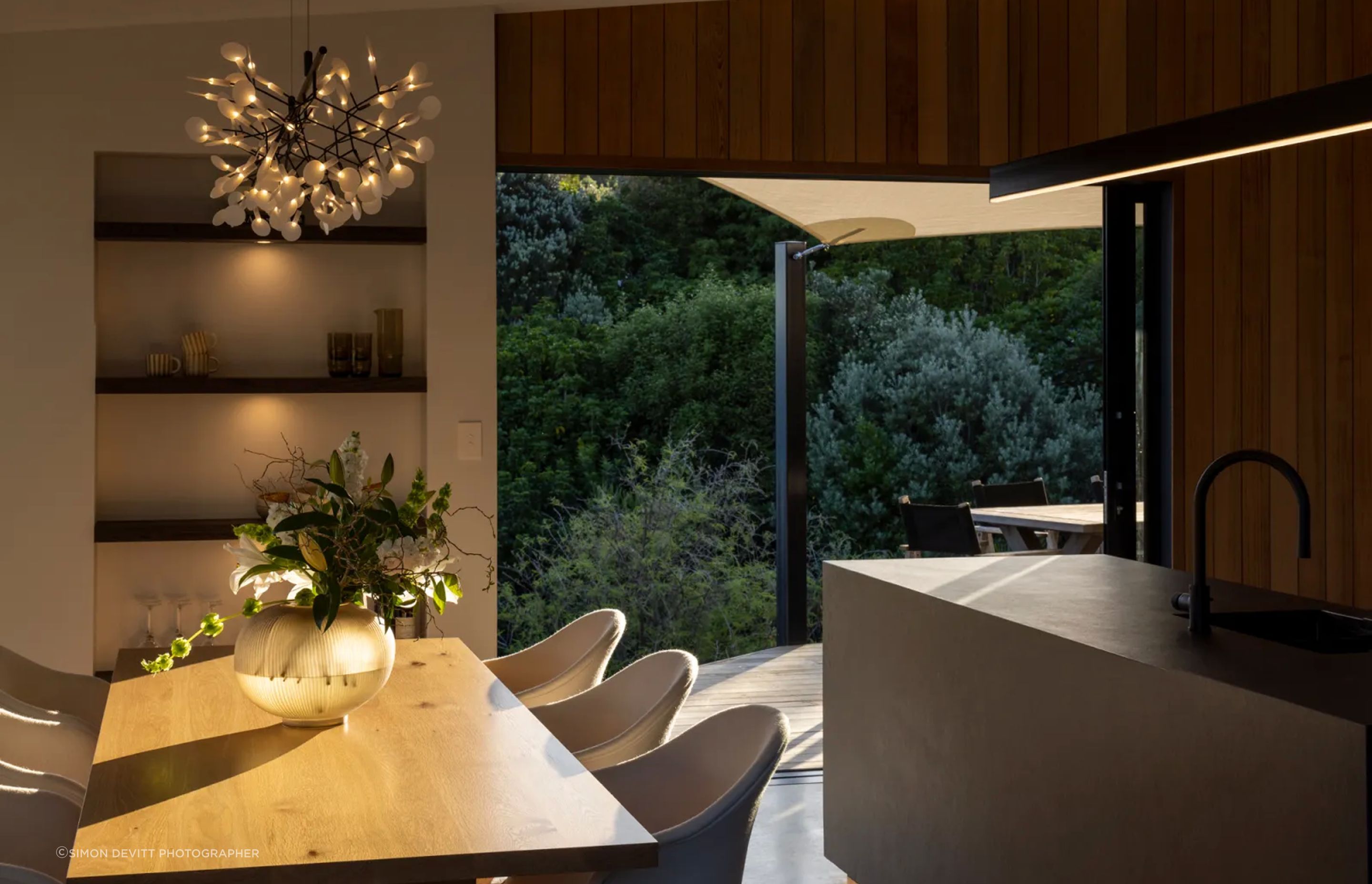 The open-plan kitchen and dining room, extending into the quiet surrounds with a sheltered outdoor living space.