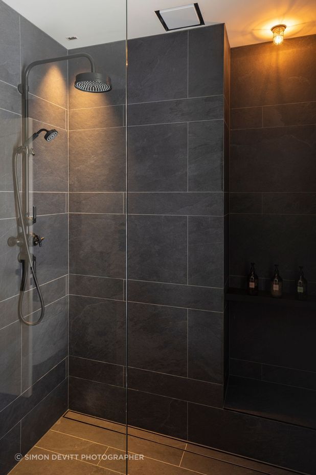 Black textured tile in the bathrooms contrasts with white board and batten that is used in the hallways.