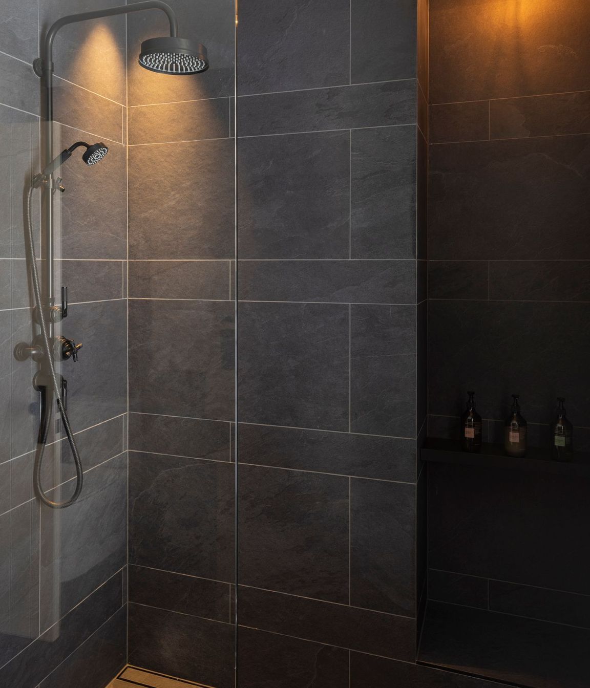 Black textured tile in the bathrooms contrasts with white board and batten that is used in the hallways.