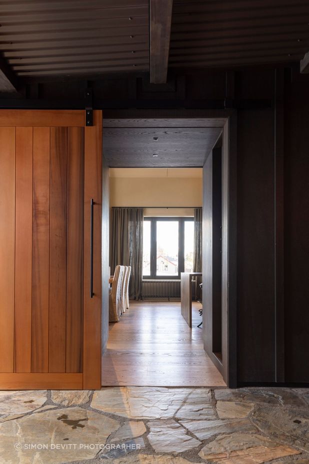 The exterior cladding and corrugated iron roof of the lean-to entrance that joins the two building forms. Clutha stone is on the floor.