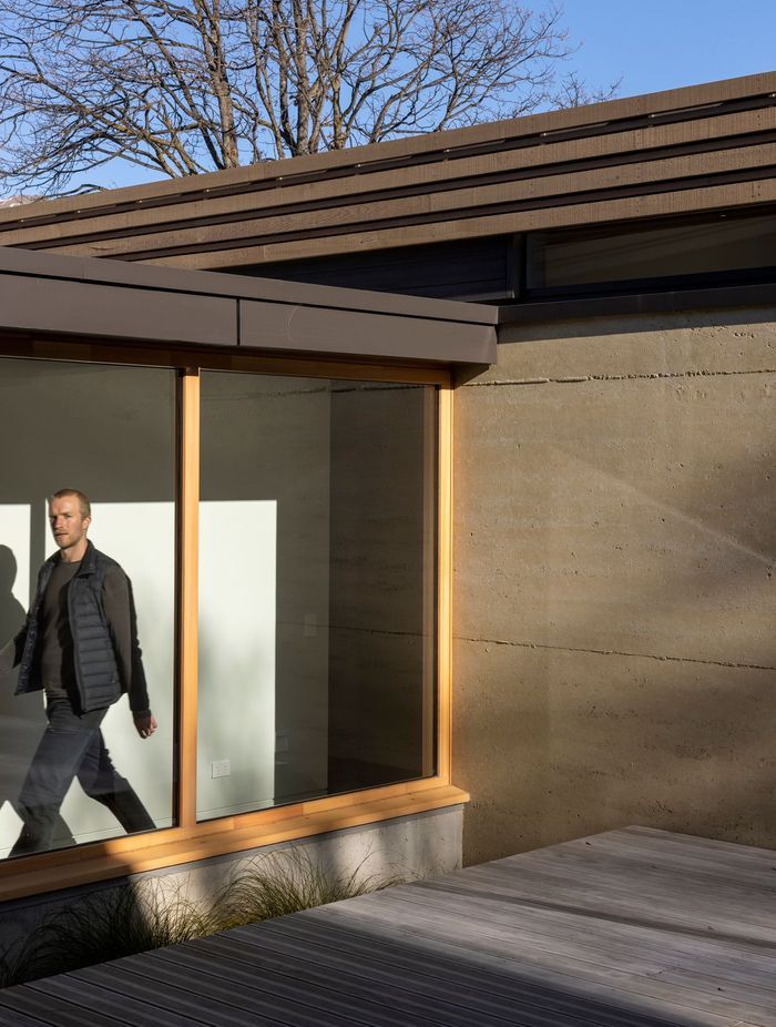 The corridor between the two pavilions, framed by large picture windows with larch joinery. | Photographer: Simon Devitt