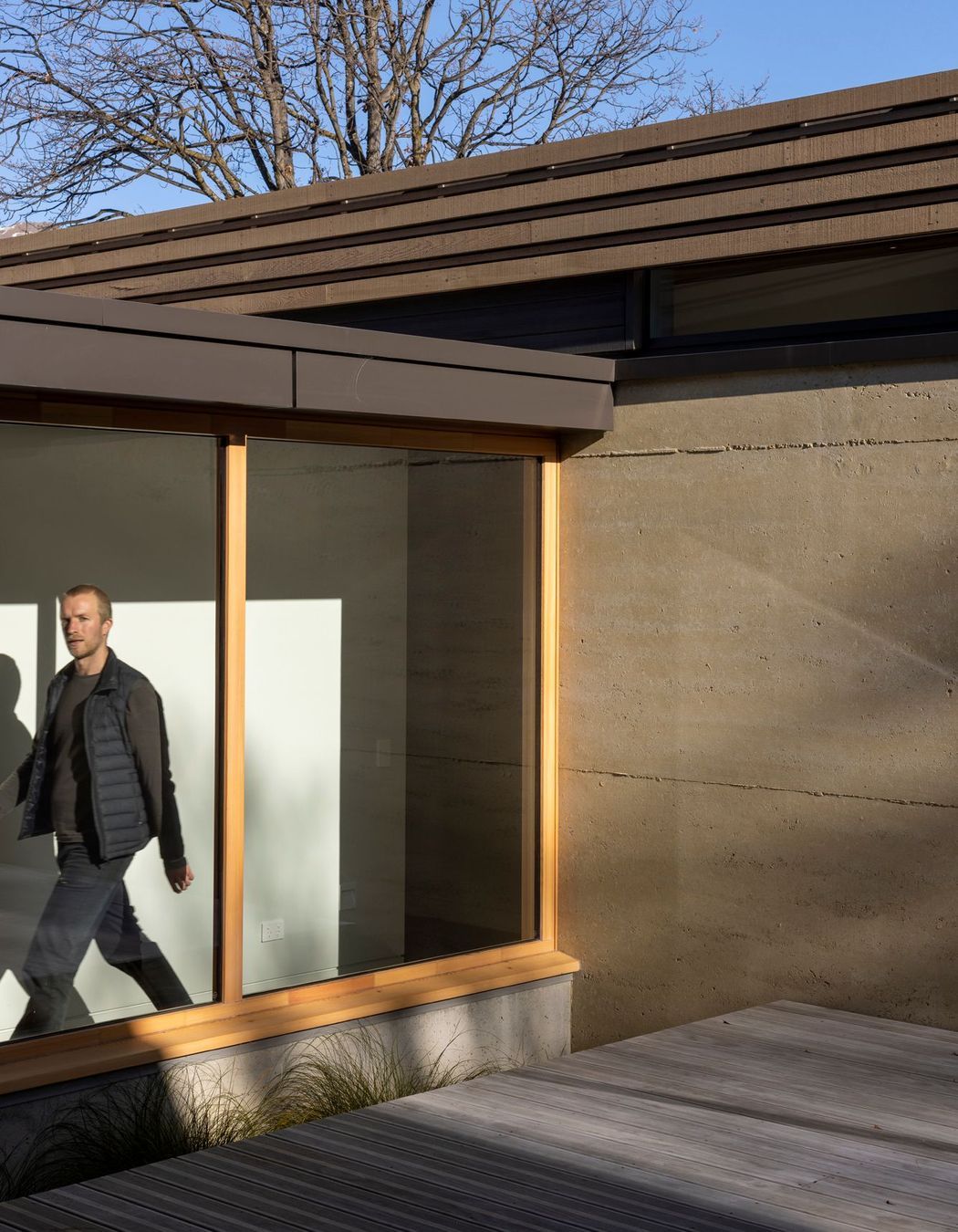 The corridor between the two pavilions, framed by large picture windows with larch joinery. | Photographer: Simon Devitt