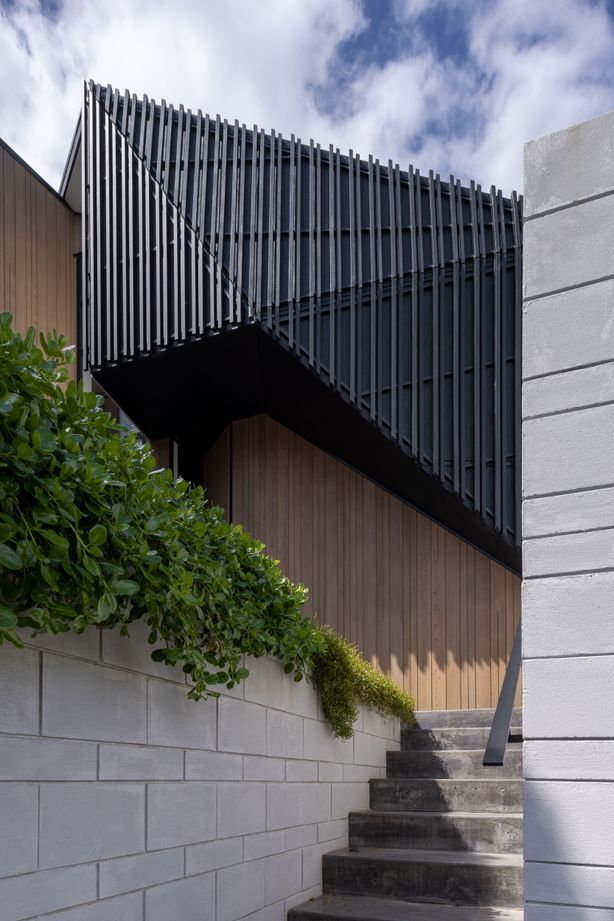 Dark trapezoidal shapes are flanked by pillar-like forms clad in cedar.