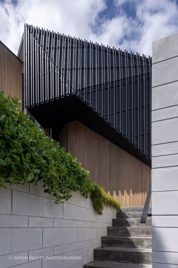 Dark trapezoidal shapes are flanked by pillar-like forms clad in cedar.