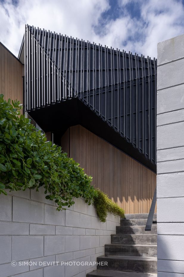 Dark trapezoidal shapes are flanked by pillar-like forms clad in cedar.