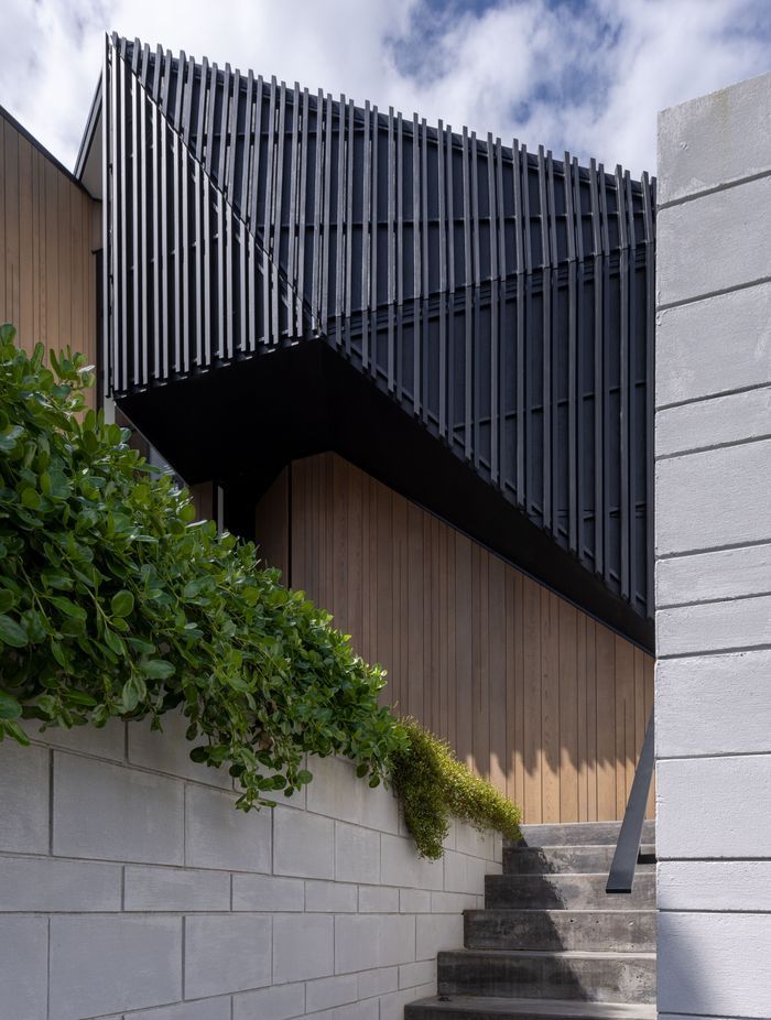 Dark trapezoidal shapes are flanked by pillar-like forms clad in cedar.