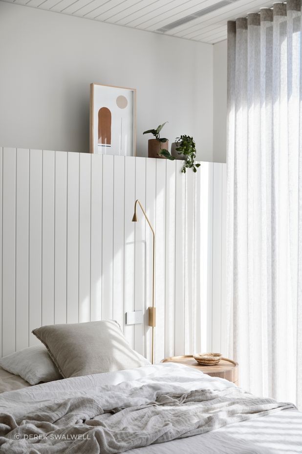 A timber lined ceiling and timber headboard offer a subtle coastal reference in the master bedroom.