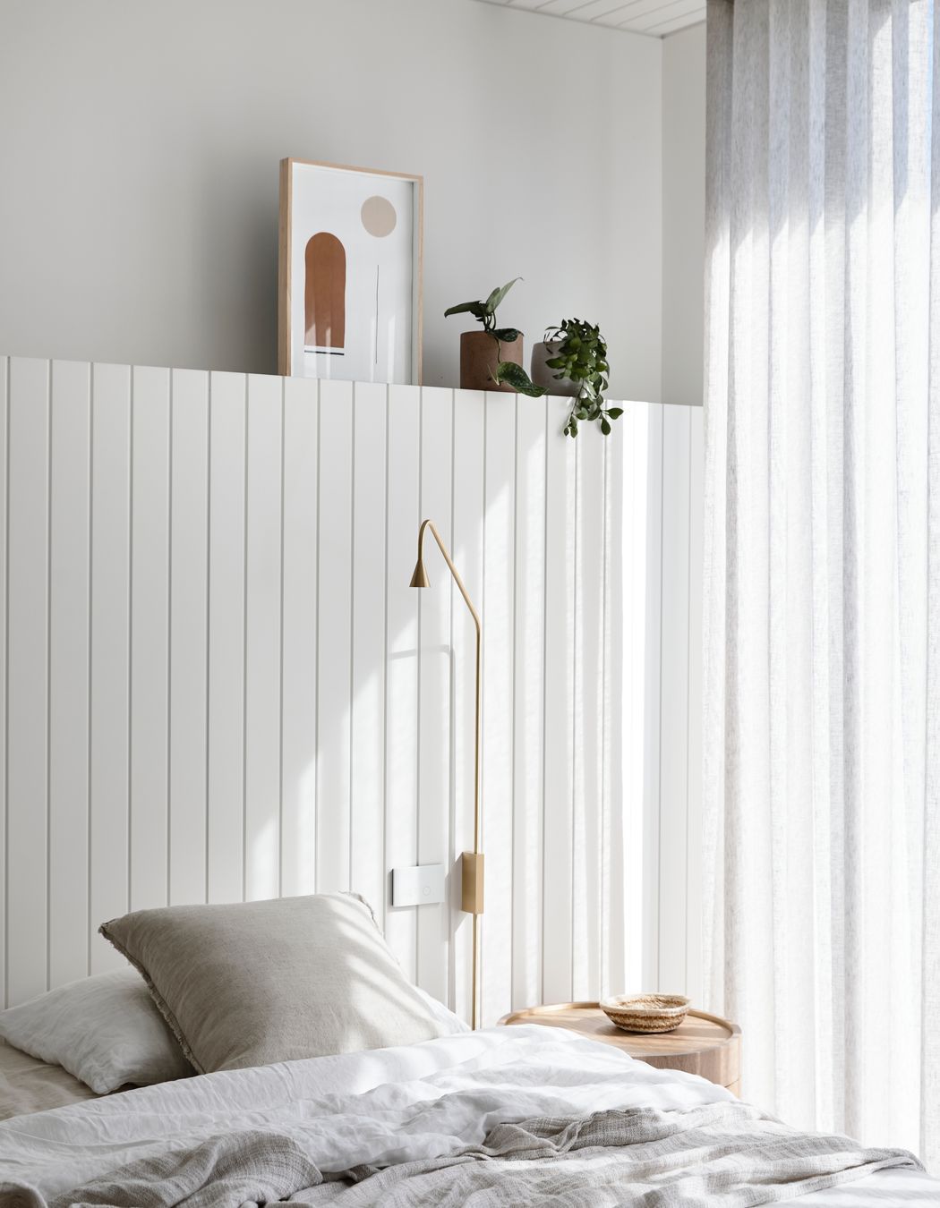 A timber lined ceiling and timber headboard offer a subtle coastal reference in the master bedroom.