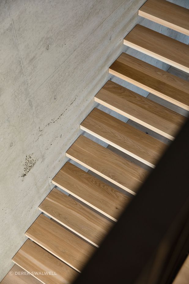 Elegant timber treads contrast against the tactile concrete wall.