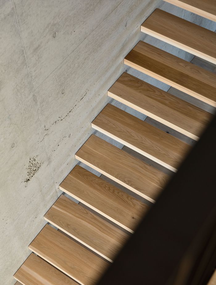 Elegant timber treads contrast against the tactile concrete wall.