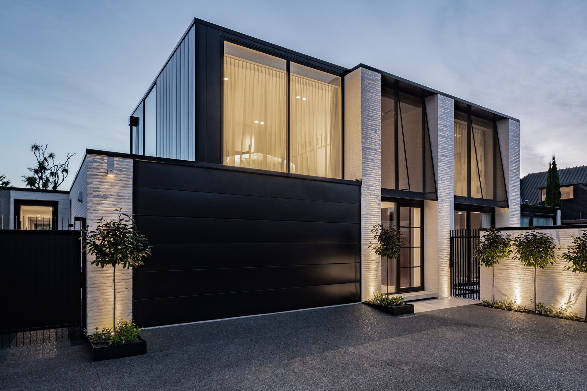 The Mediterranean-influenced house designed by Tobin Smith of Common Architecture is sited in a quiet spot in a cul de sac and down a right of way. The fixed awnings on the upstairs windows are steel frames with sheer fabric, for sun control and privacy. “During the day these read as jet black awnings but at night, you get that beautiful transparency through them.”