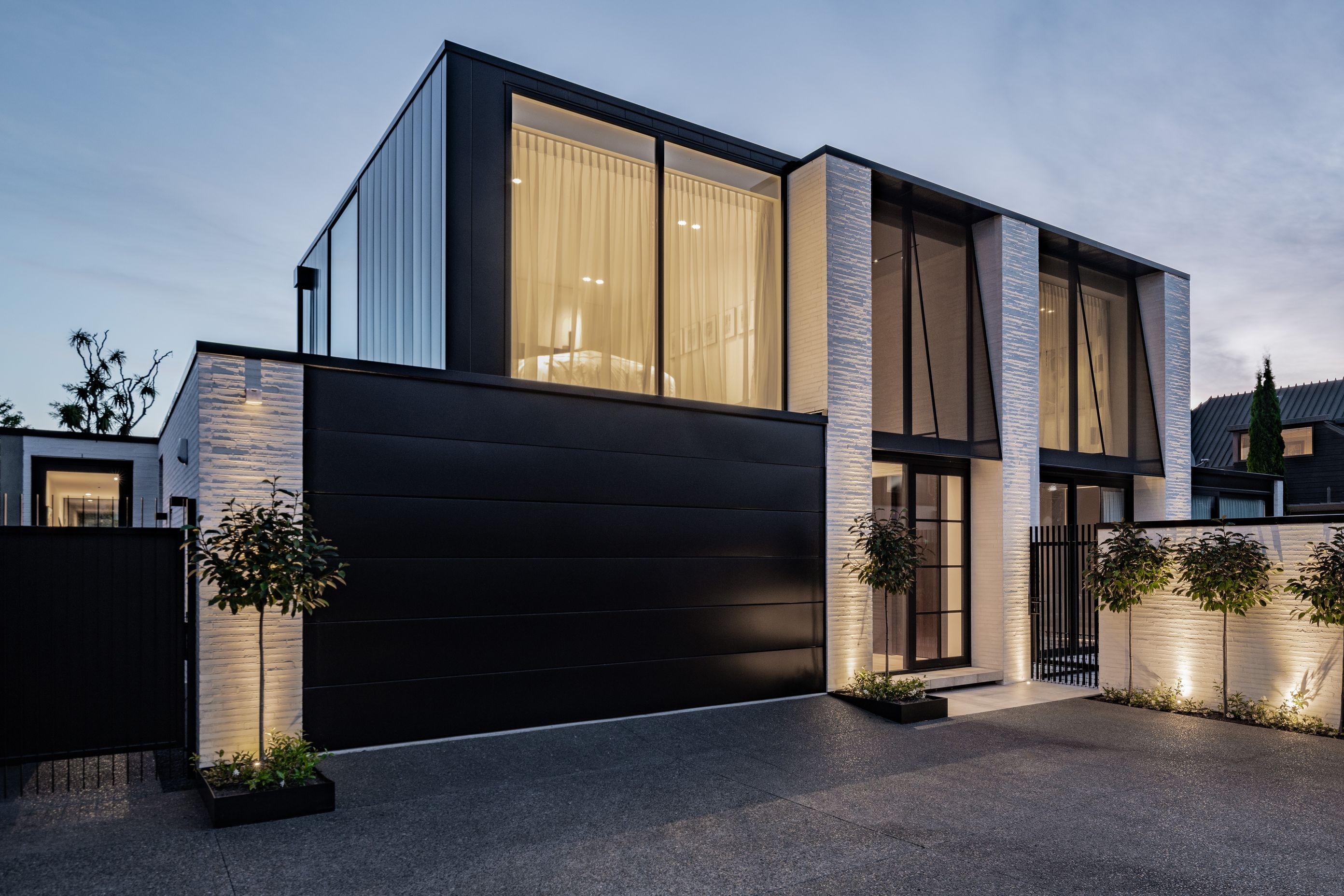 The Mediterranean-influenced house designed by Tobin Smith of Common Architecture is sited in a quiet spot in a cul de sac and down a right of way. The fixed awnings on the upstairs windows are steel frames with sheer fabric, for sun control and privacy. “During the day these read as jet black awnings but at night, you get that beautiful transparency through them.”