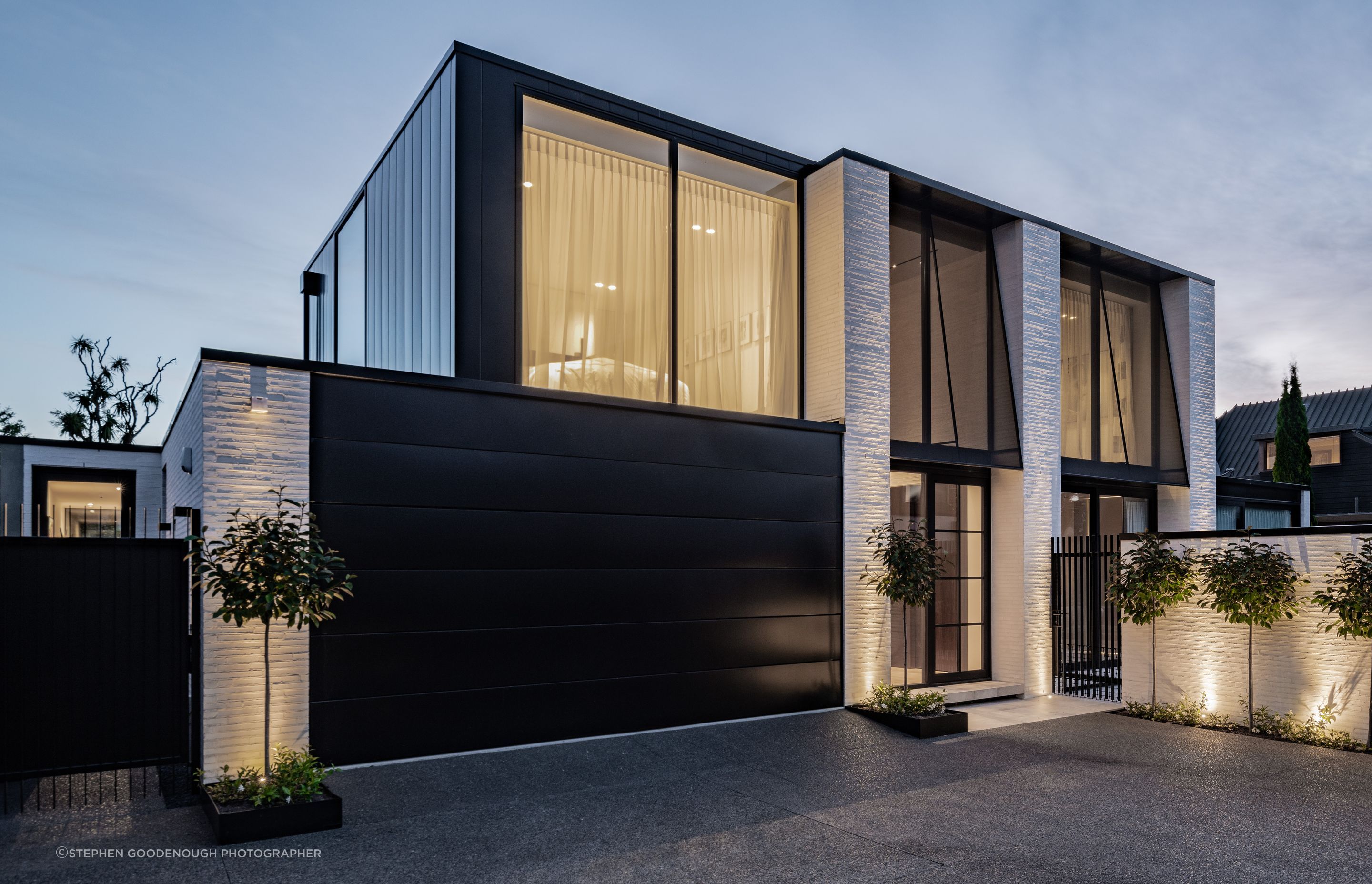 The Mediterranean-influenced house designed by Tobin Smith of Common Architecture is sited in a quiet spot in a cul de sac and down a right of way. The fixed awnings on the upstairs windows are steel frames with sheer fabric, for sun control and privacy. “During the day these read as jet black awnings but at night, you get that beautiful transparency through them.”