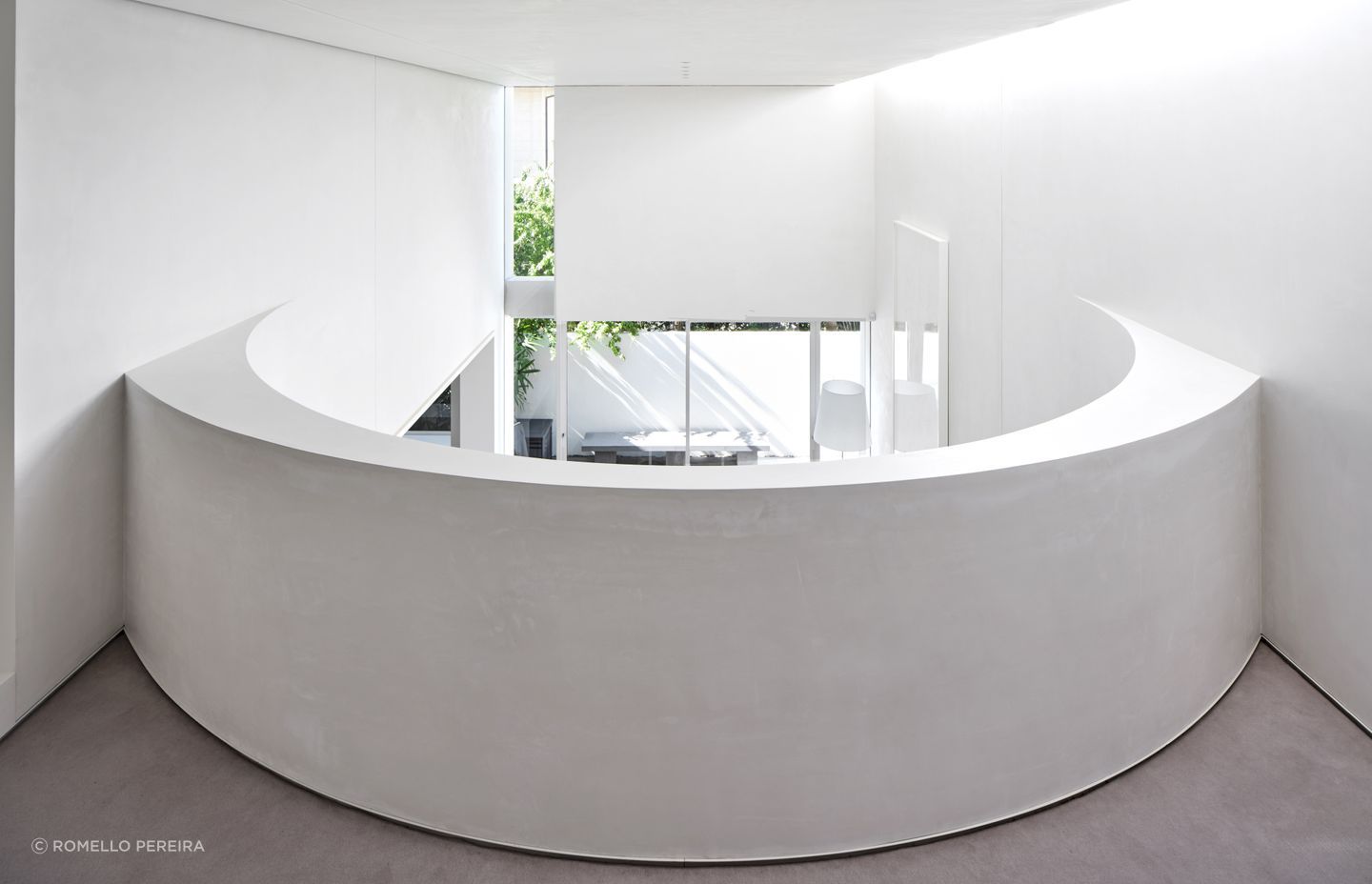 The curved wall of the mezzanine, looking down over the living and outdoor spaces.