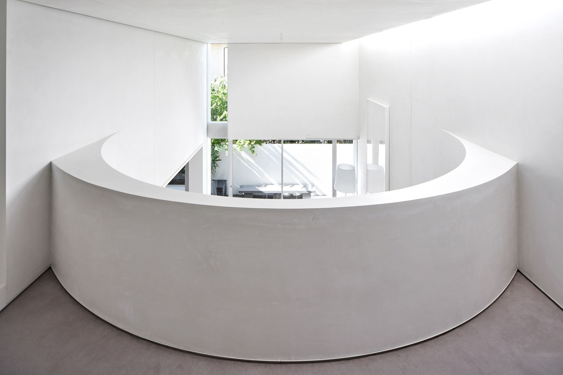 The curved wall of the mezzanine, looking down over the living and outdoor spaces.
