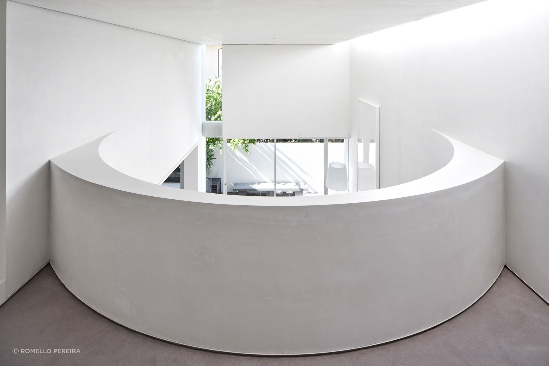 The curved wall of the mezzanine, looking down over the living and outdoor spaces.