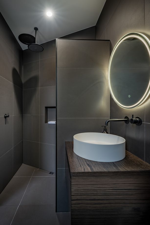 A guest bathroom and bedroom were decided on late in the design and were tucked in behind the angled garage. “That created an interesting shape and the shower shows that.”