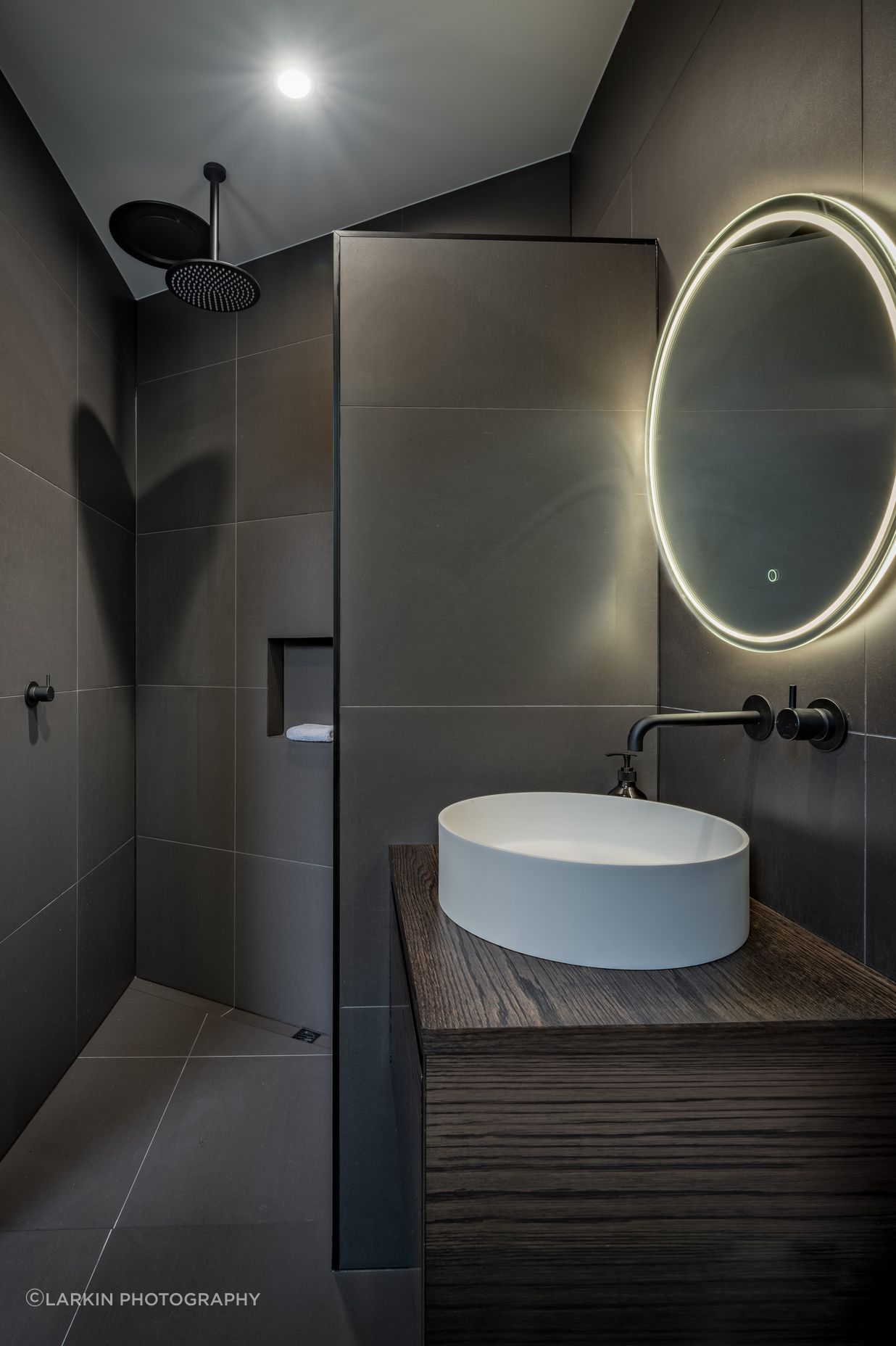 A guest bathroom and bedroom were decided on late in the design and were tucked in behind the angled garage. “That created an interesting shape and the shower shows that.”