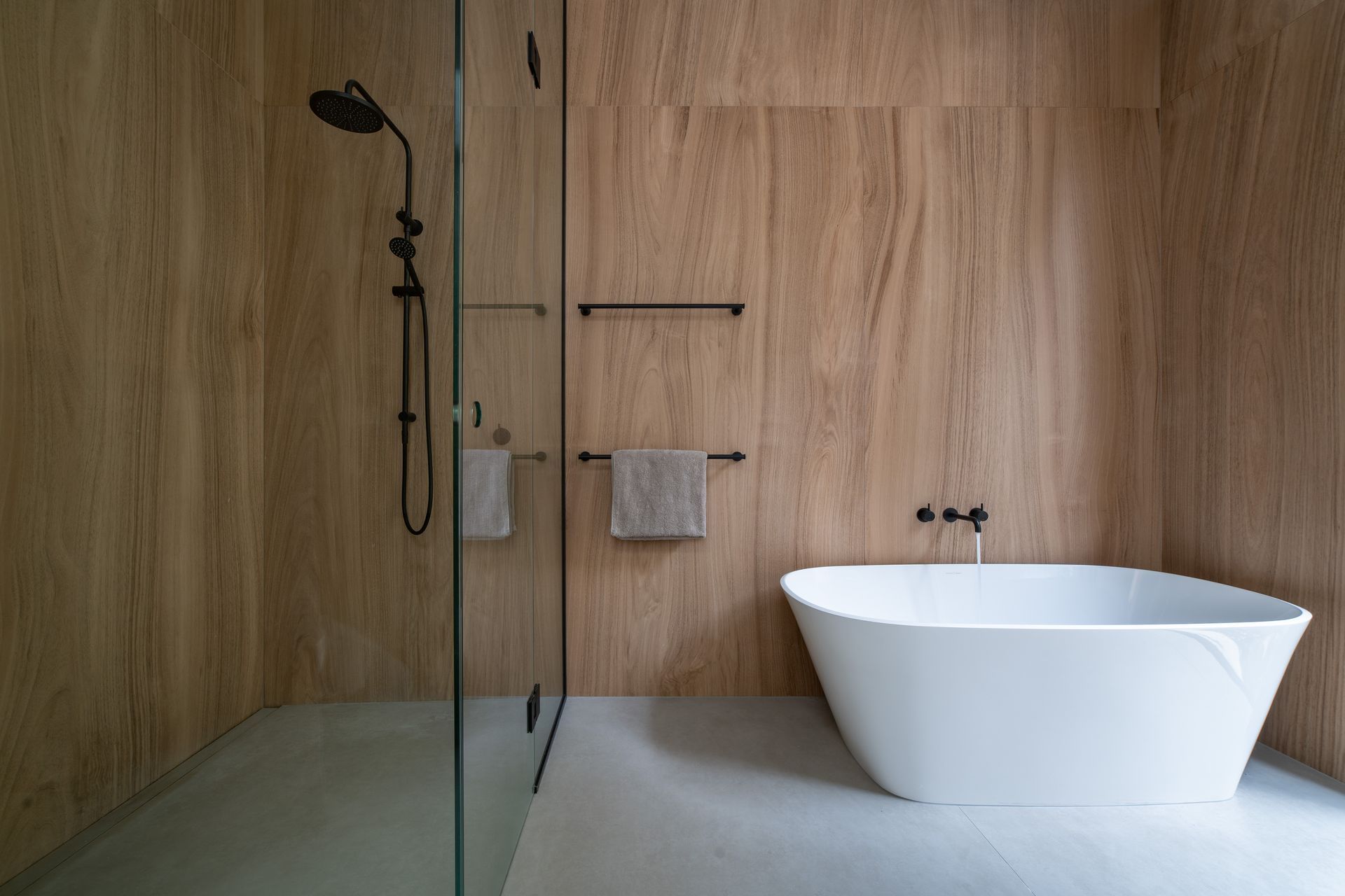 The bathroom continues the minimal approach to interior design with large format timber-look tiles and glass.
