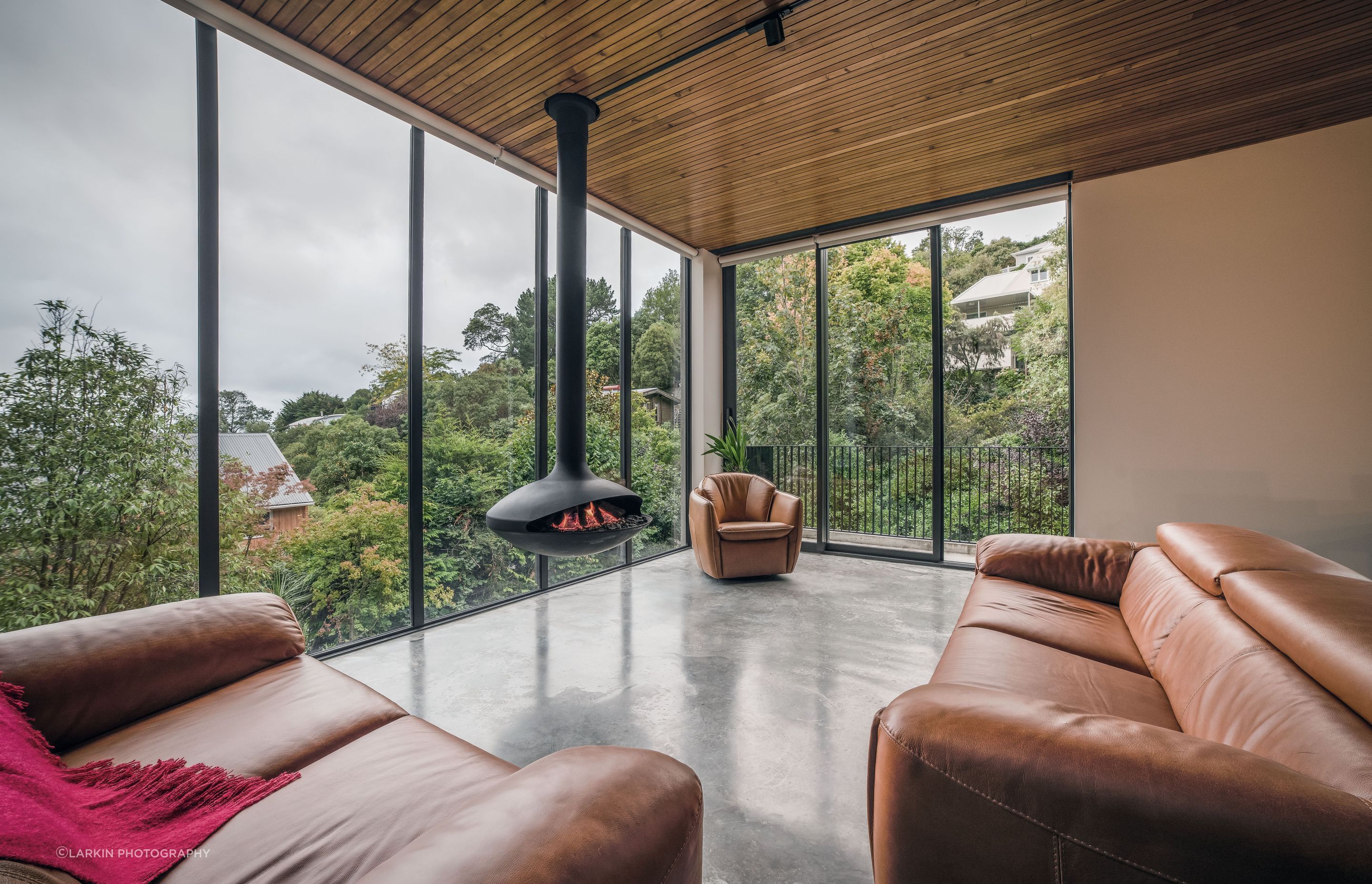 The living space is warmed by Siberian larch-lined ceilings, rust-toned sofas, and a suspended fire.