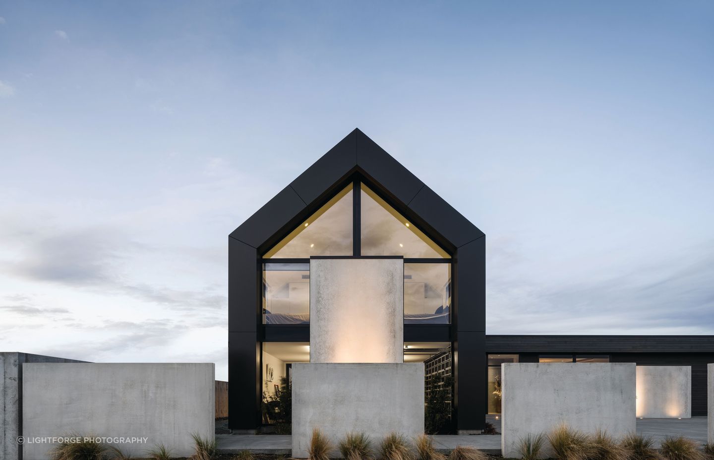 The two-storey gabled form uses vertical cladding, while the single-storey living wing is clad horizontally in cedar.