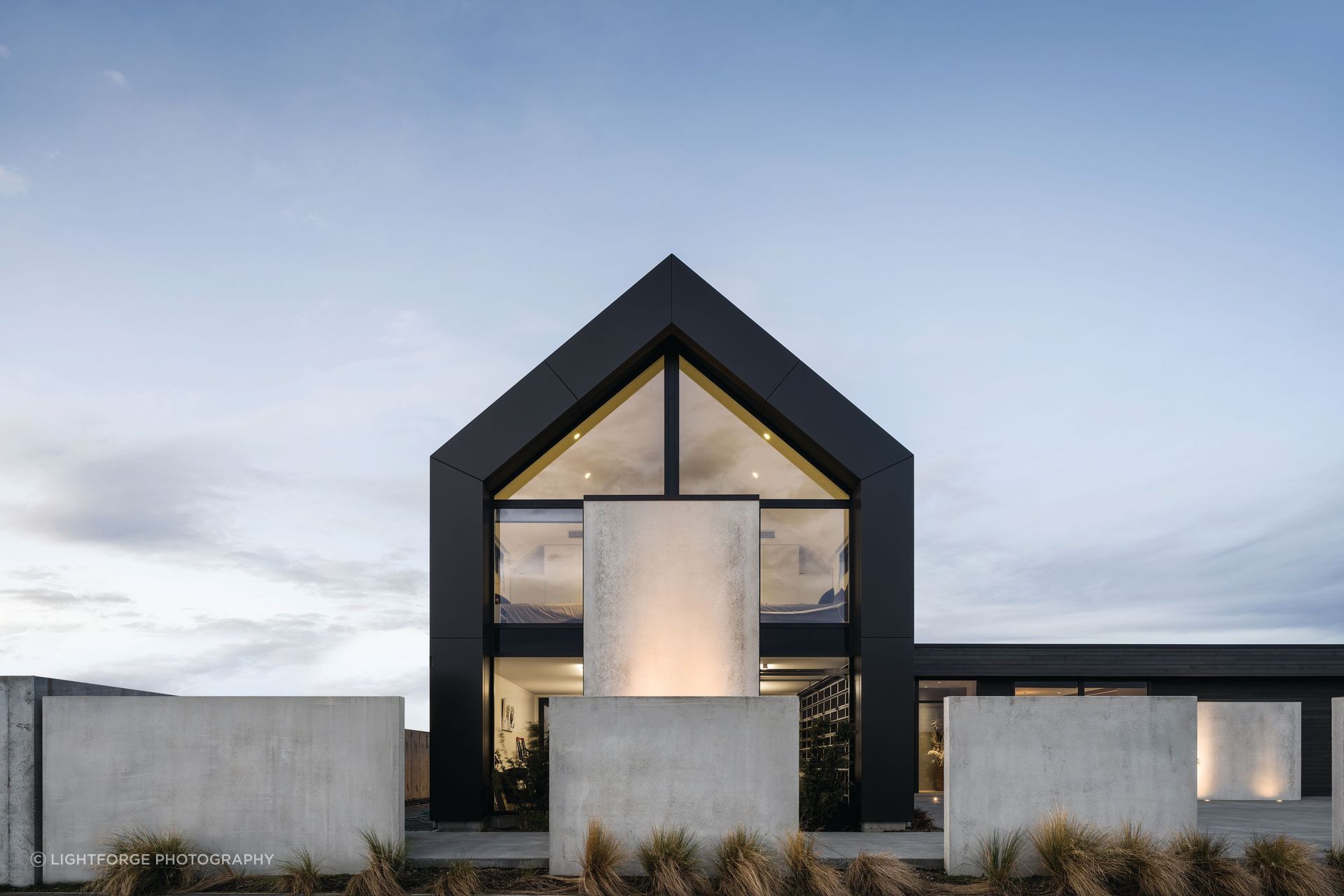 The two-storey gabled form uses vertical cladding, while the single-storey living wing is clad horizontally in cedar.