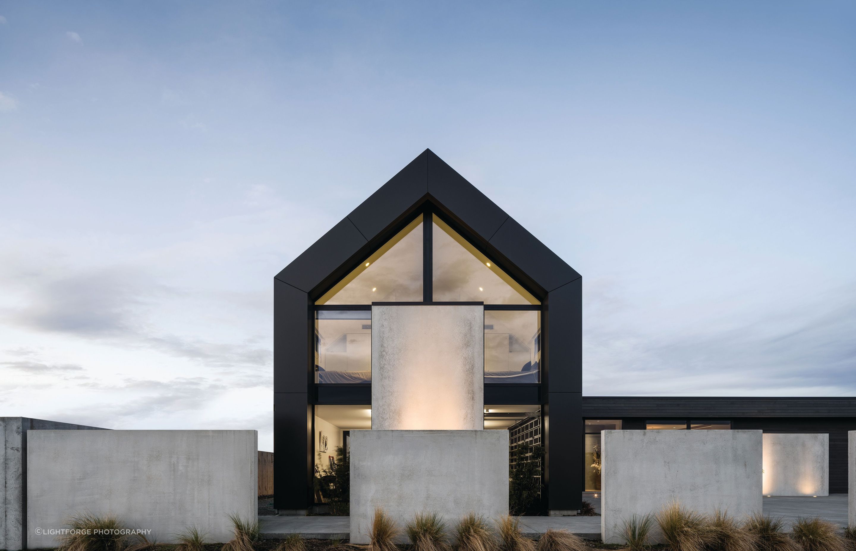 The two-storey gabled form uses vertical cladding, while the single-storey living wing is clad horizontally in cedar.