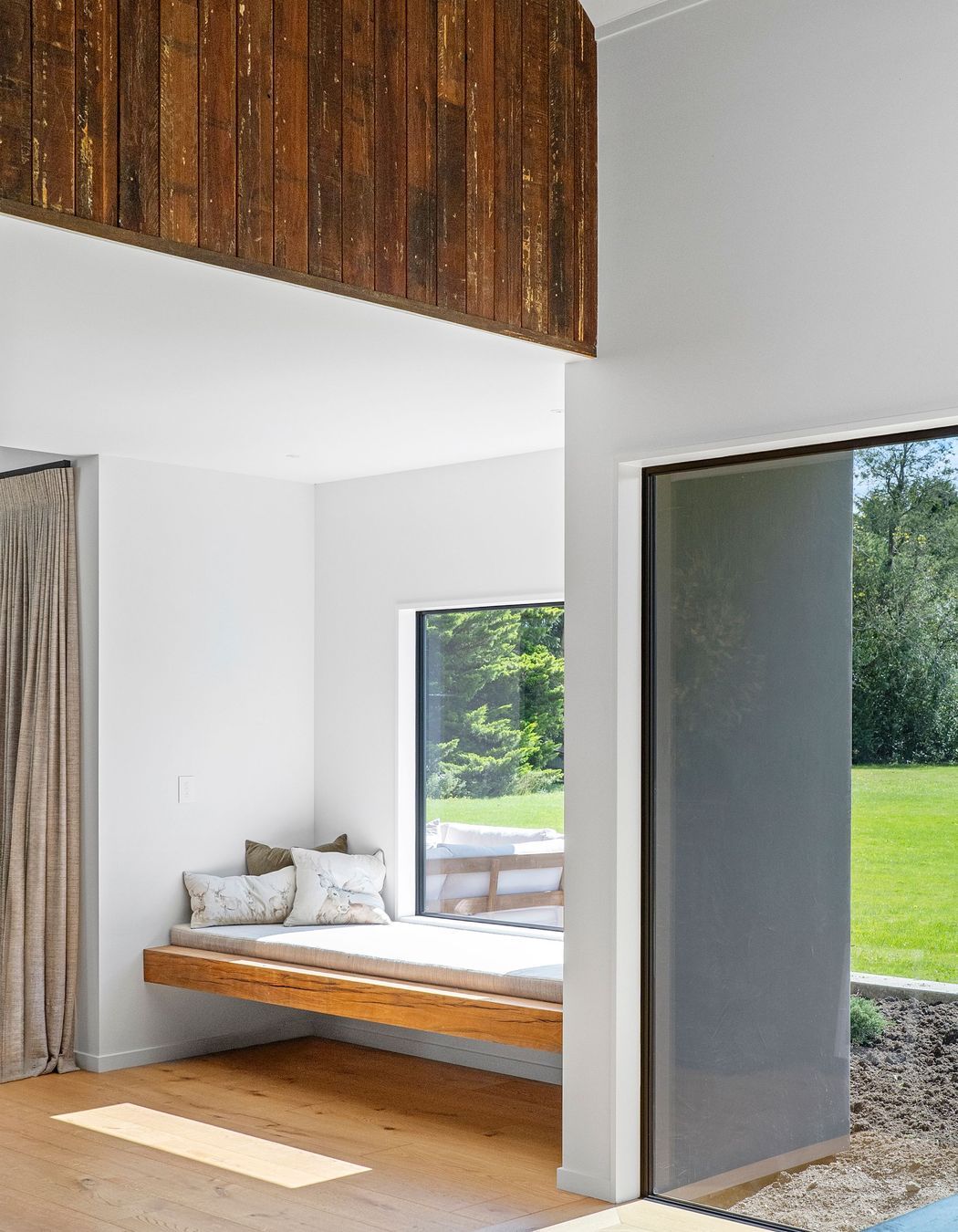 The window seat is a perfect space of refuge overlooking the green lawn.