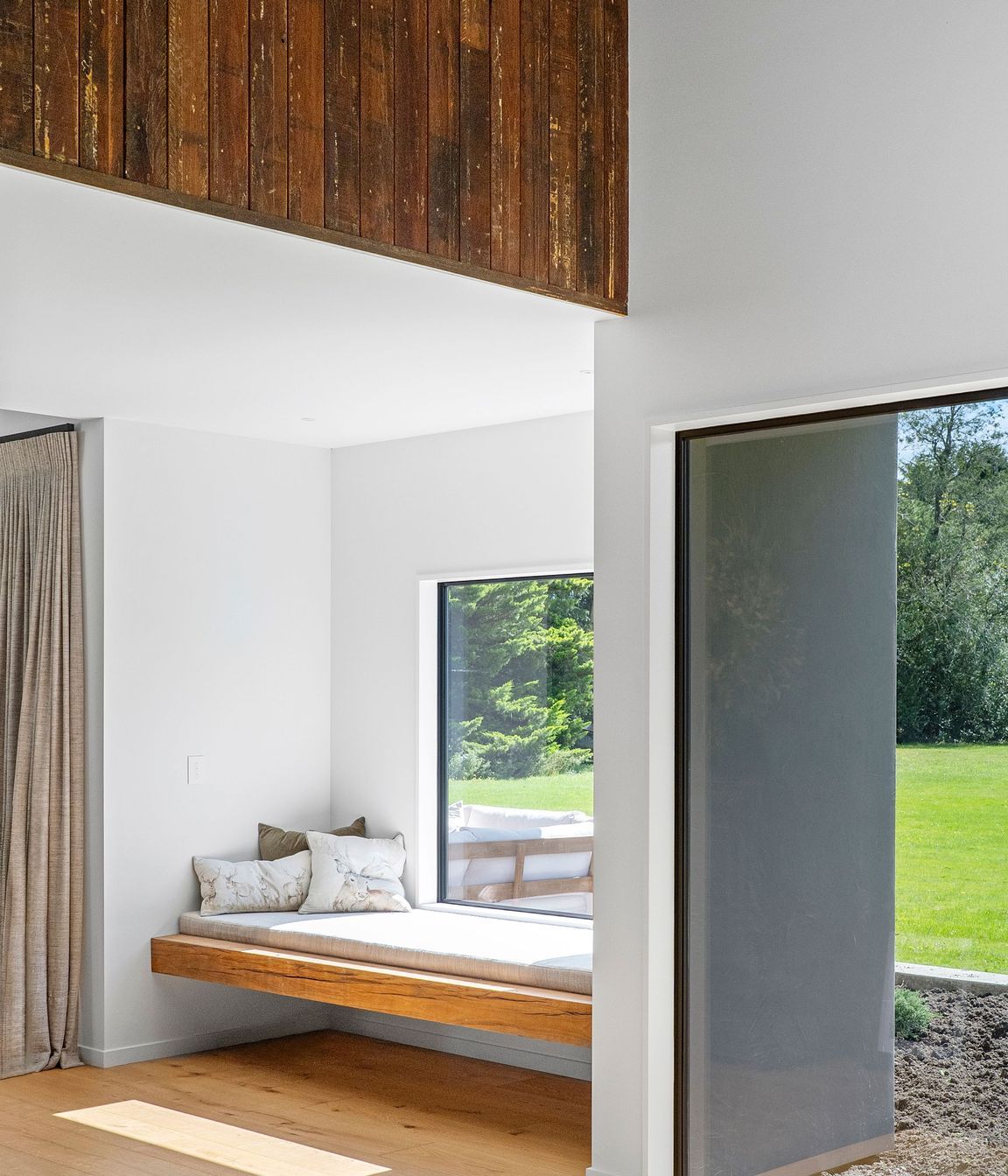 The window seat is a perfect space of refuge overlooking the green lawn.