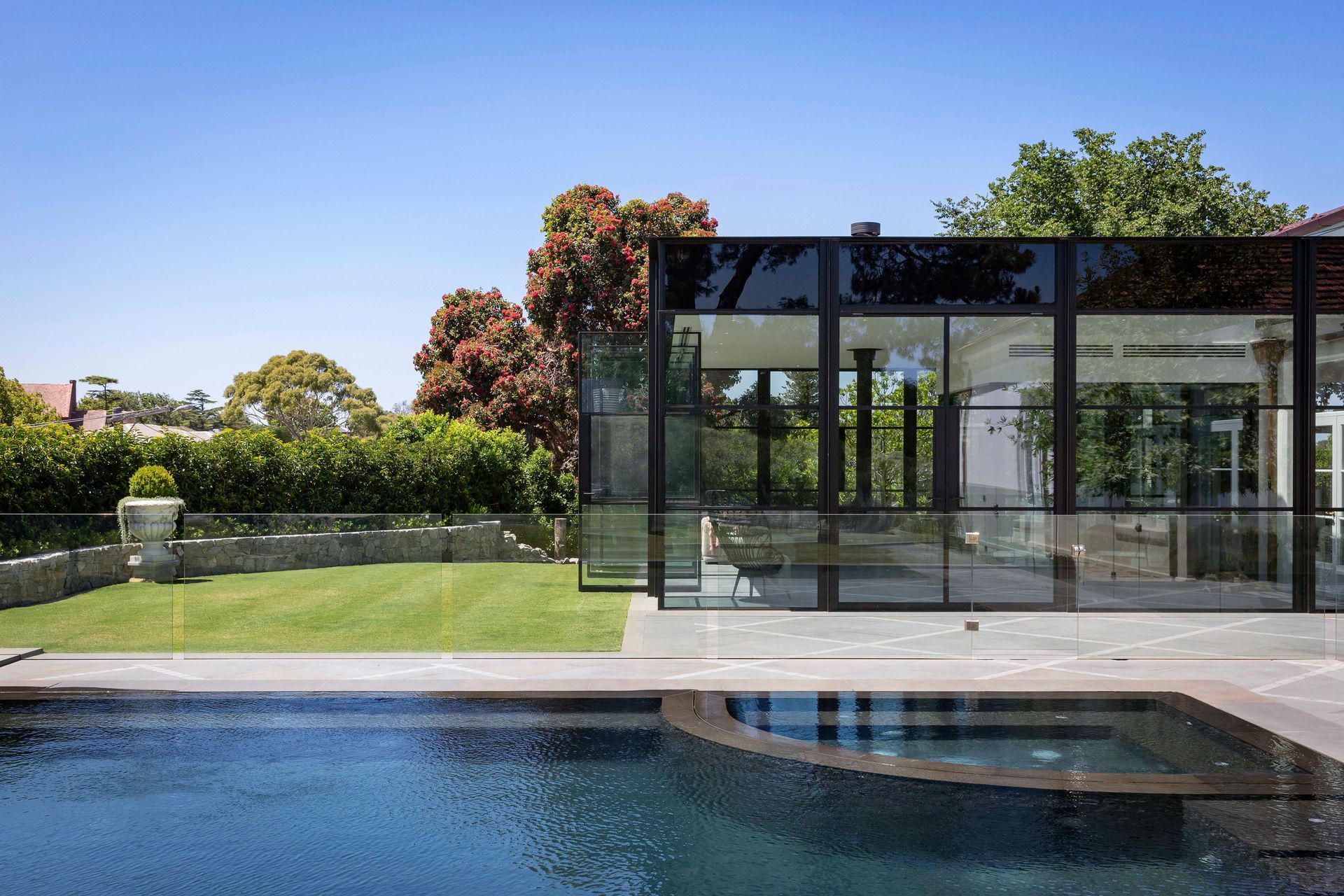 The line between indoors and out is blurred with floor-to-ceiling glazing and doors that open out onto the grass and patio area.