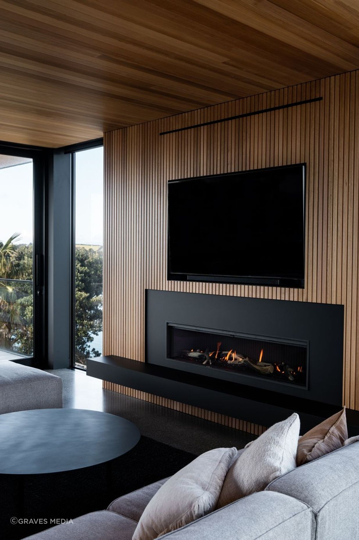 The living area centres around the elegant fireplace, sophistically surrounded by matte-black Fenix and oak paneling.
