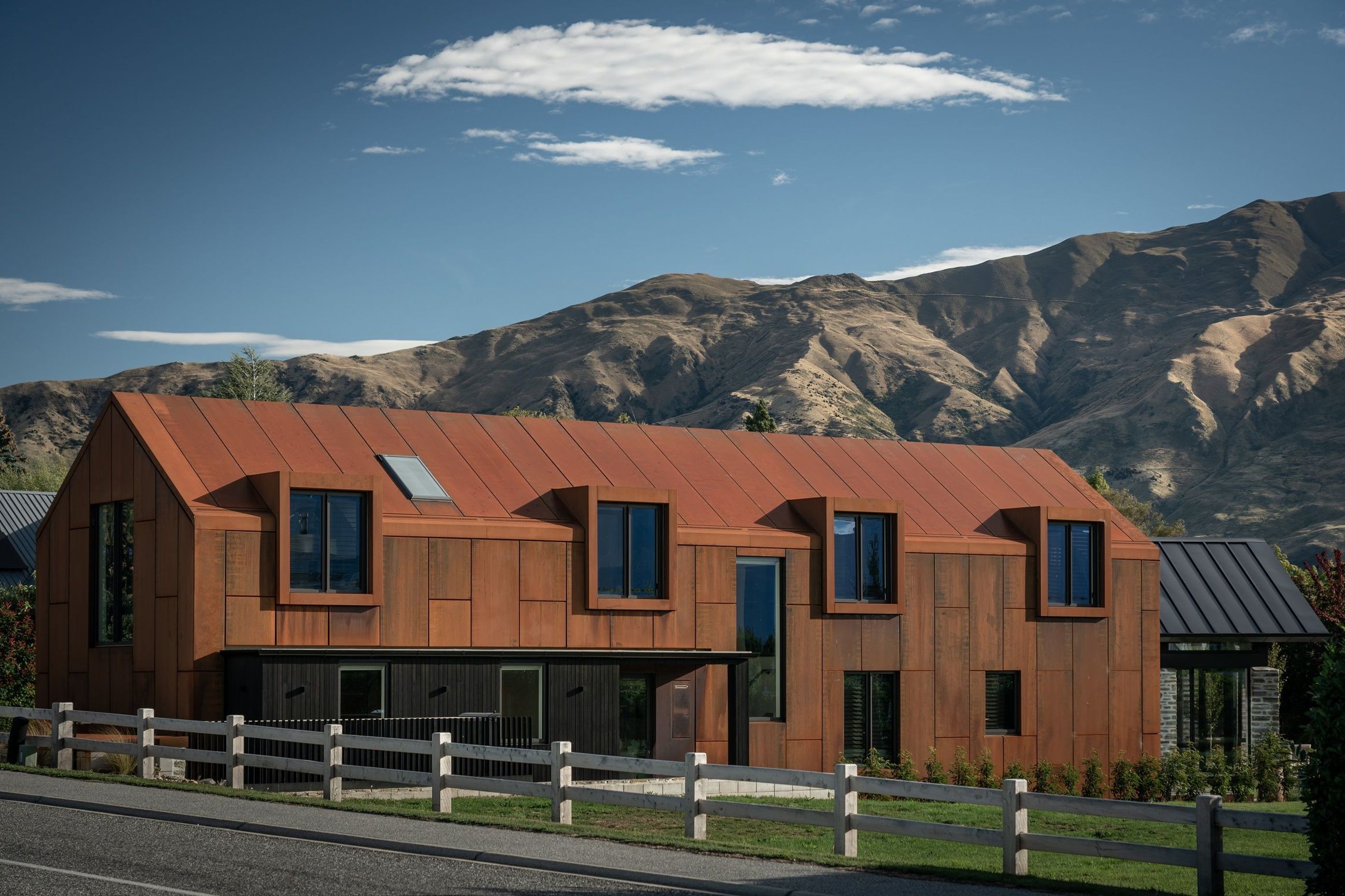 The large corten gable form echoes the form of the mountain ranges beyond.