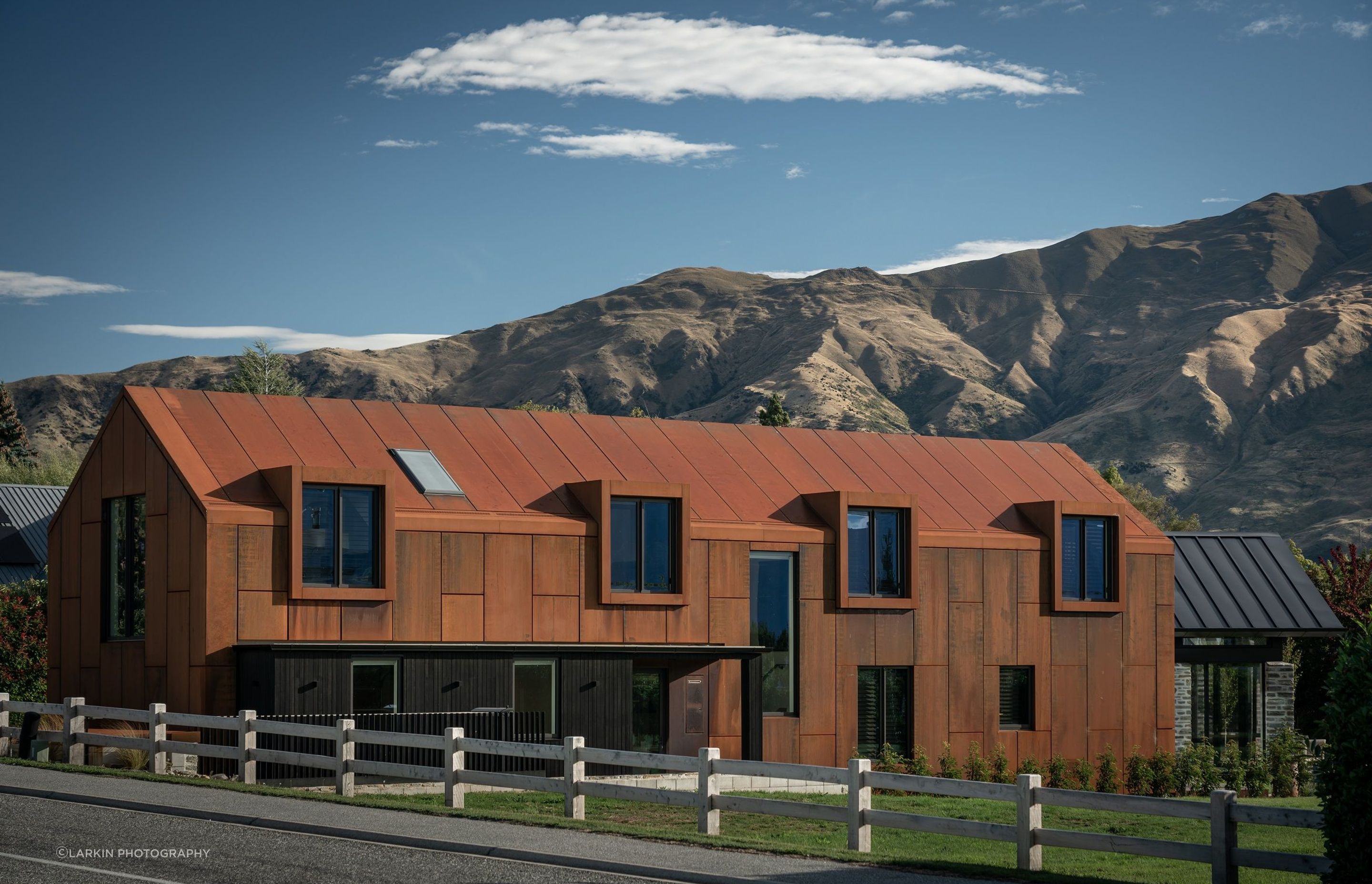 The large corten gable form echoes the form of the mountain ranges beyond.