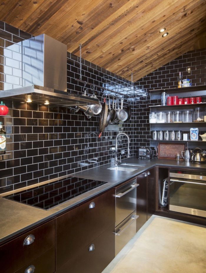 Glossy black subway tiles clad the walls of the kitchen.